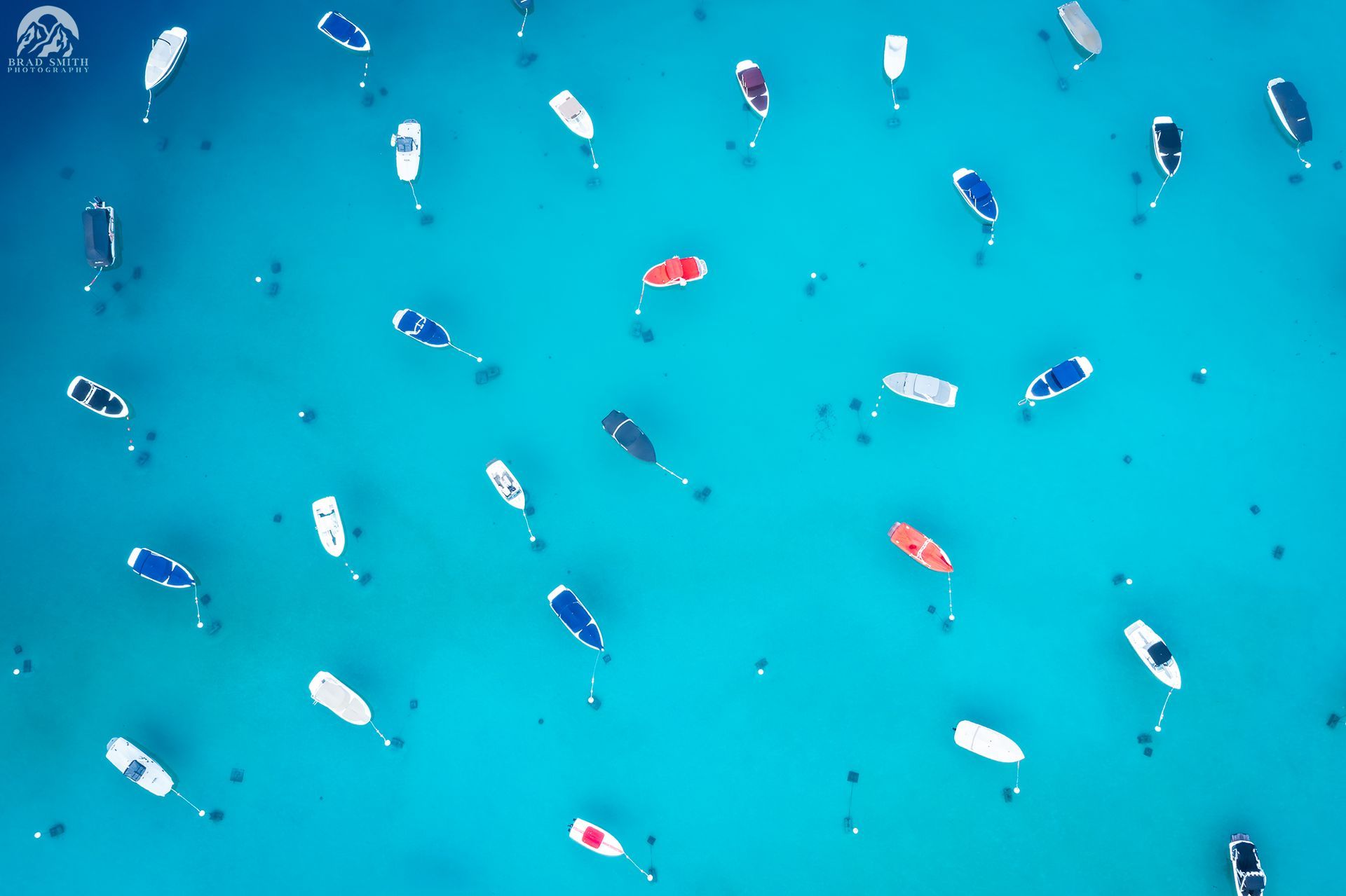 Aerial view of colorful kayaks and paddleboards floating in bright blue water
