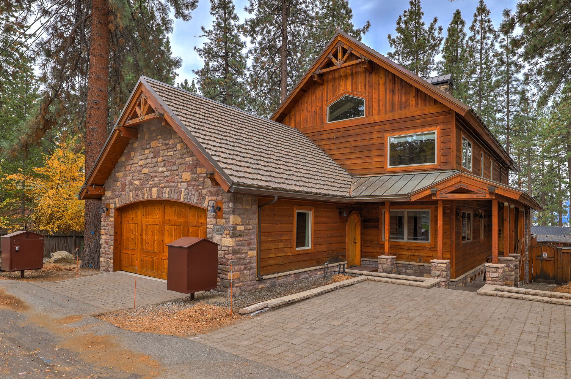Rustic wooden cabin with stone accents and a garage in a forest setting