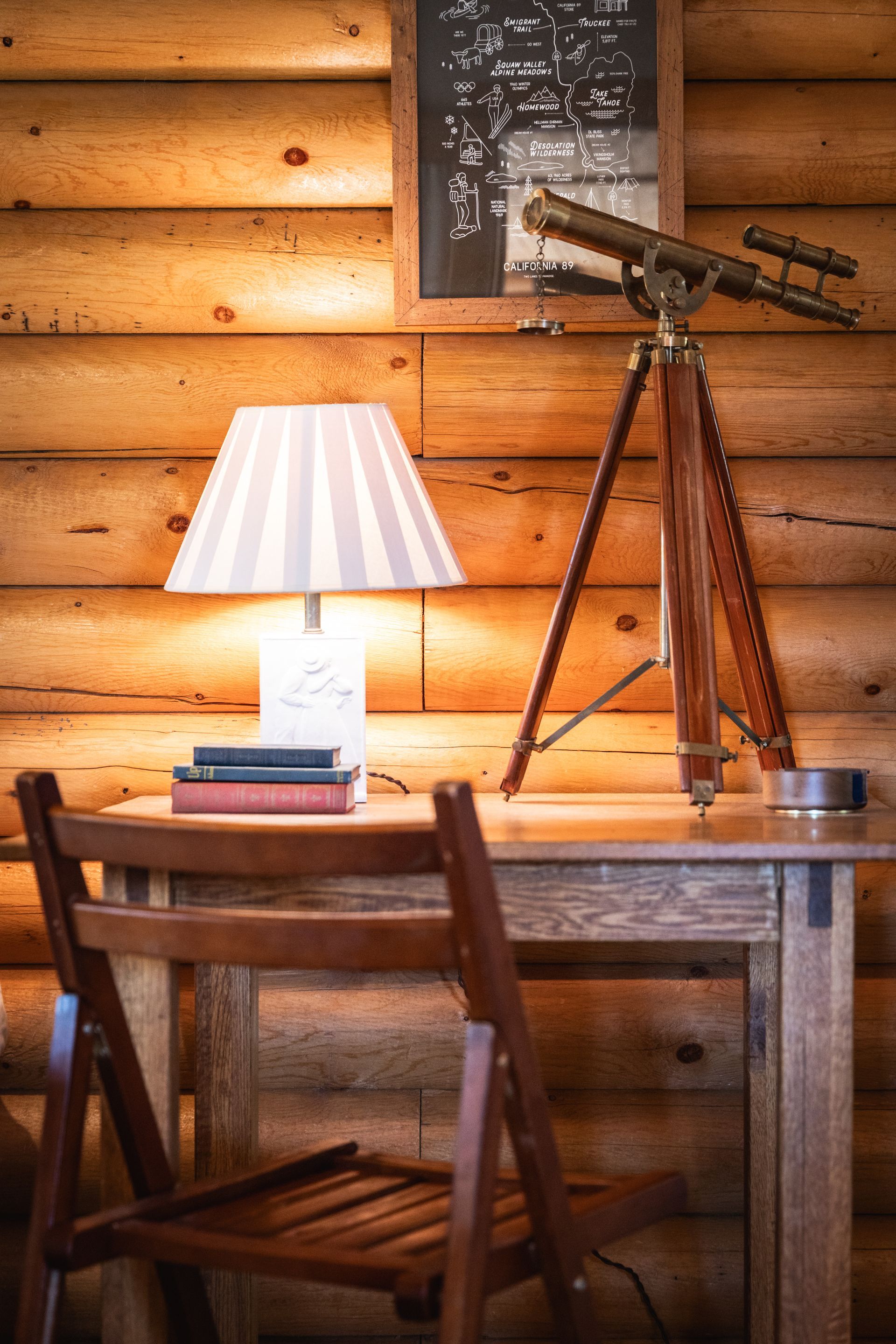 Wooden study with desk lamp, telescope, and chair in a rustic log cabin room