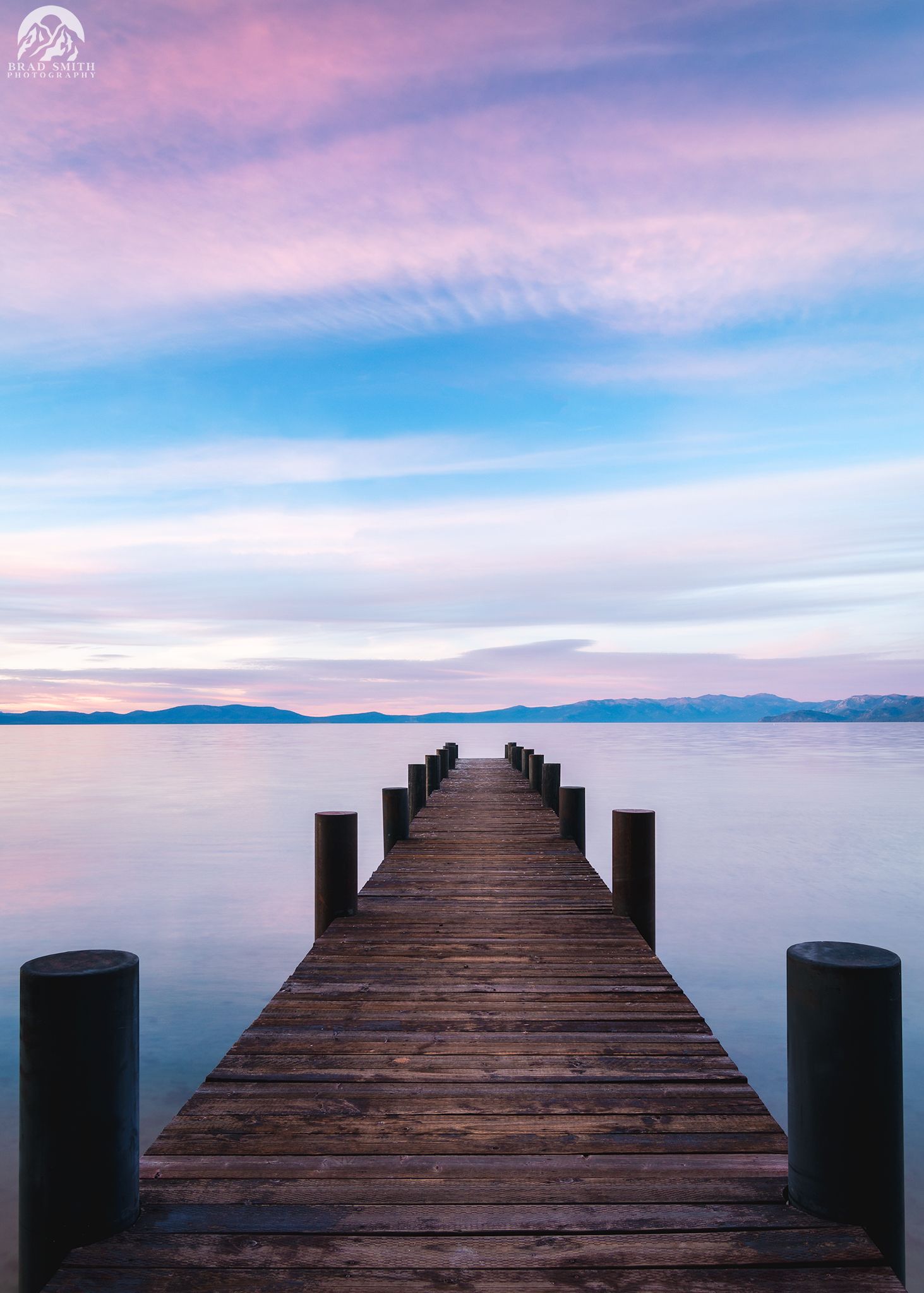 Wooden pier stretching into calm water under a pink and blue sunset sky