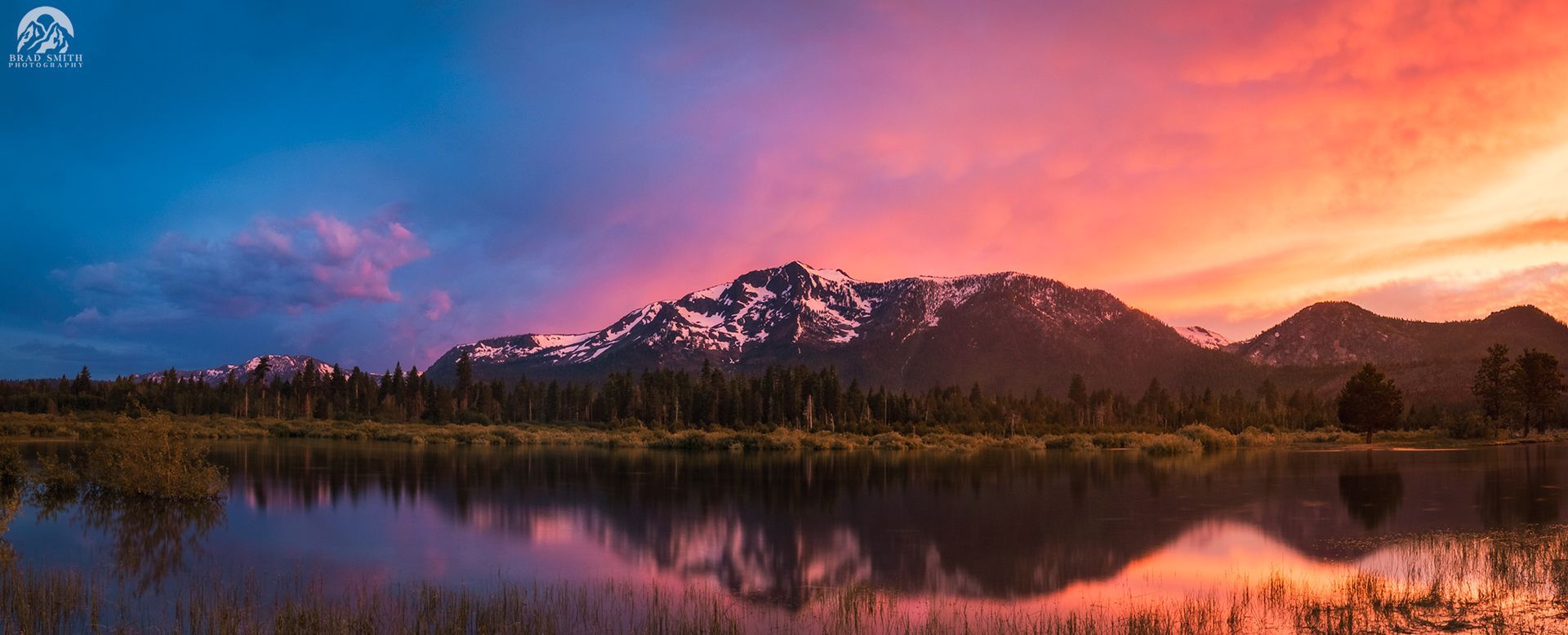 Snowy mountain reflected in a calm lake at sunset, with pink and blue sky.