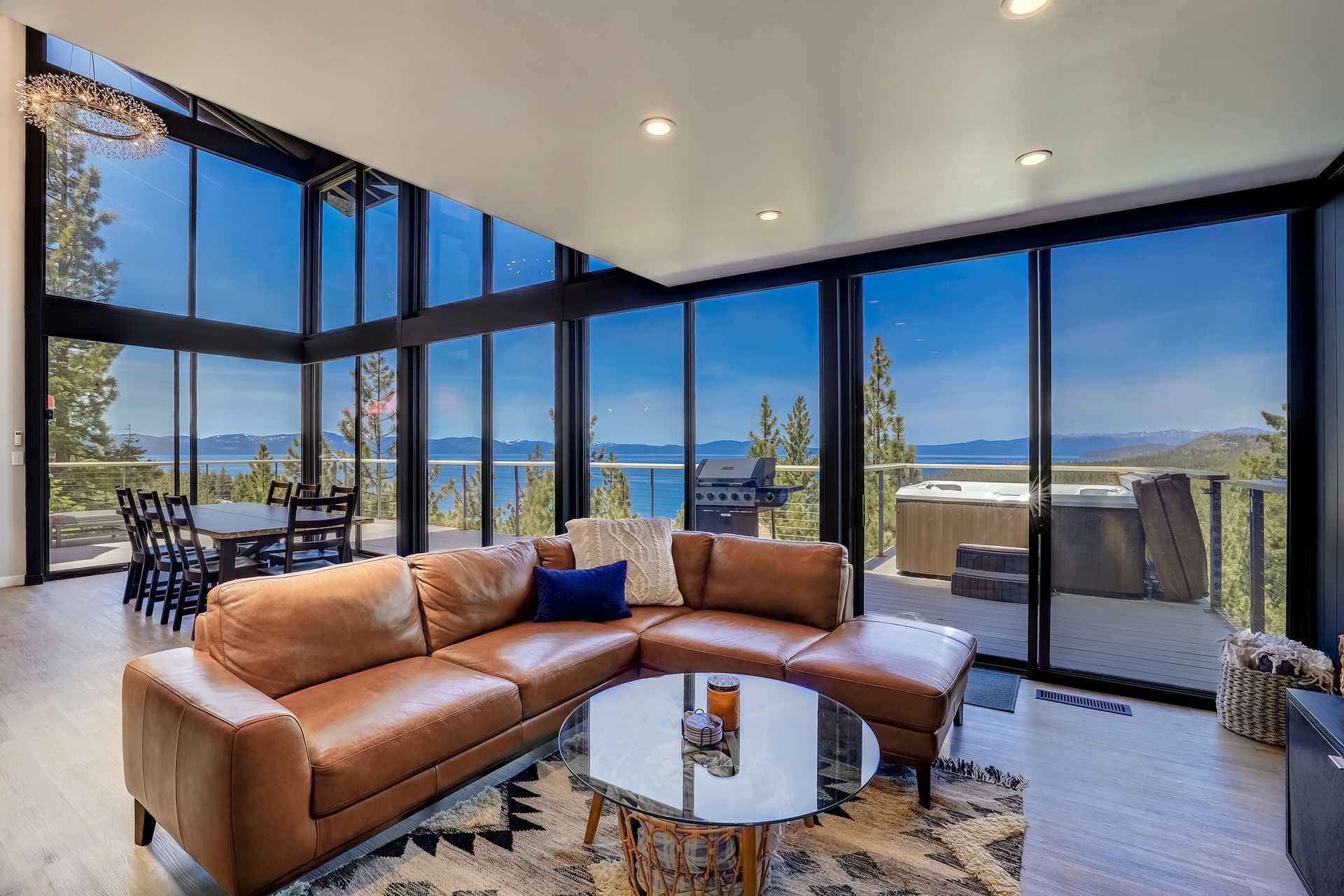Modern living room with tan sectional, glass walls, and ocean views