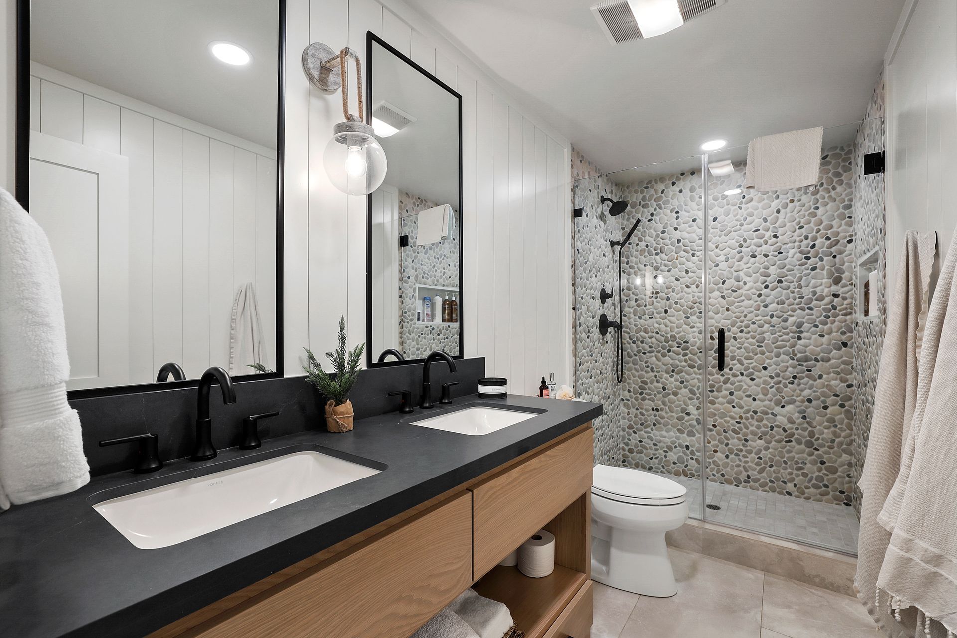 Modern bathroom with black vanity, large mirror, and tiled walk-in shower