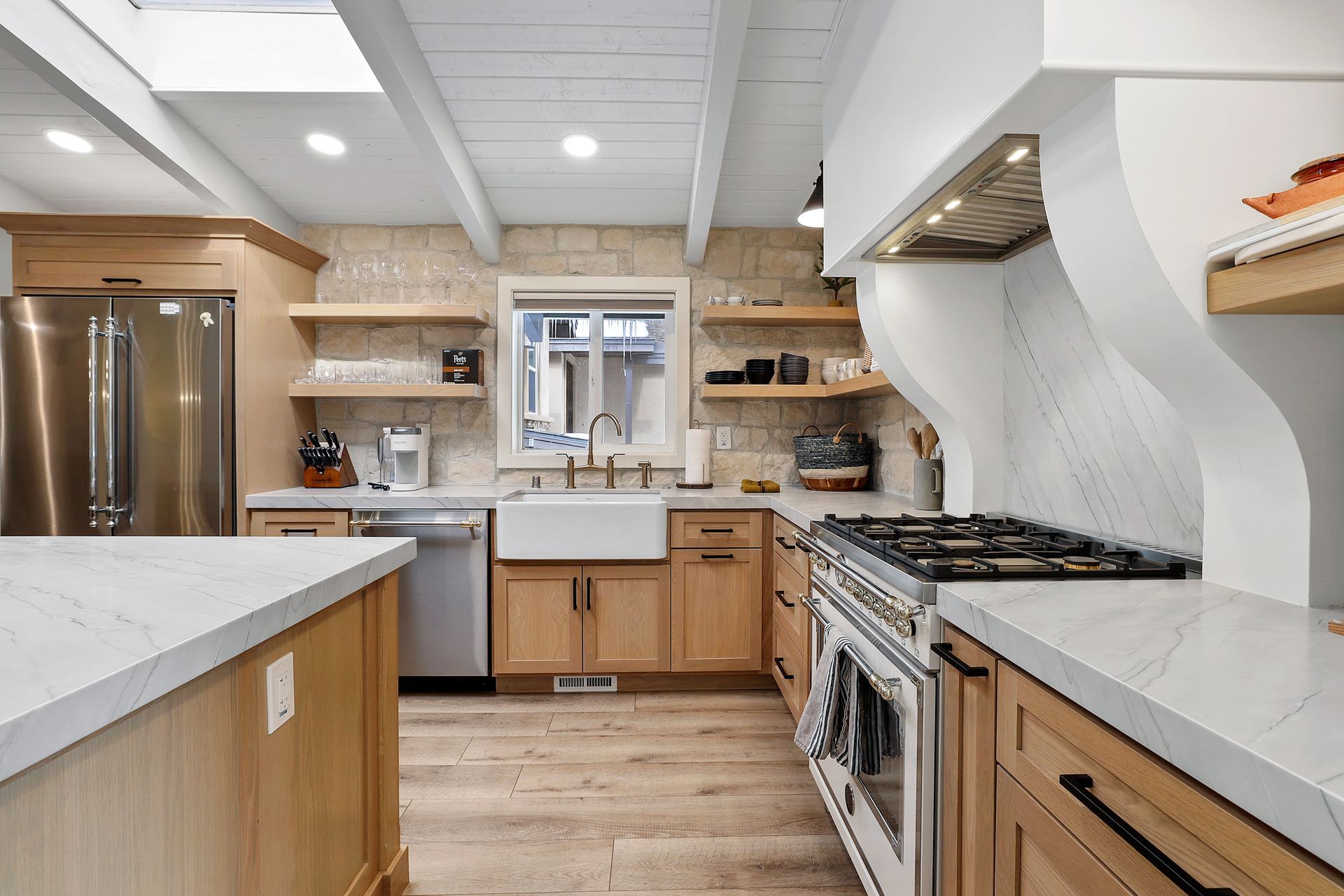 Bright modern kitchen with wood cabinets, white countertops, stainless appliances, and a farmhouse sink.