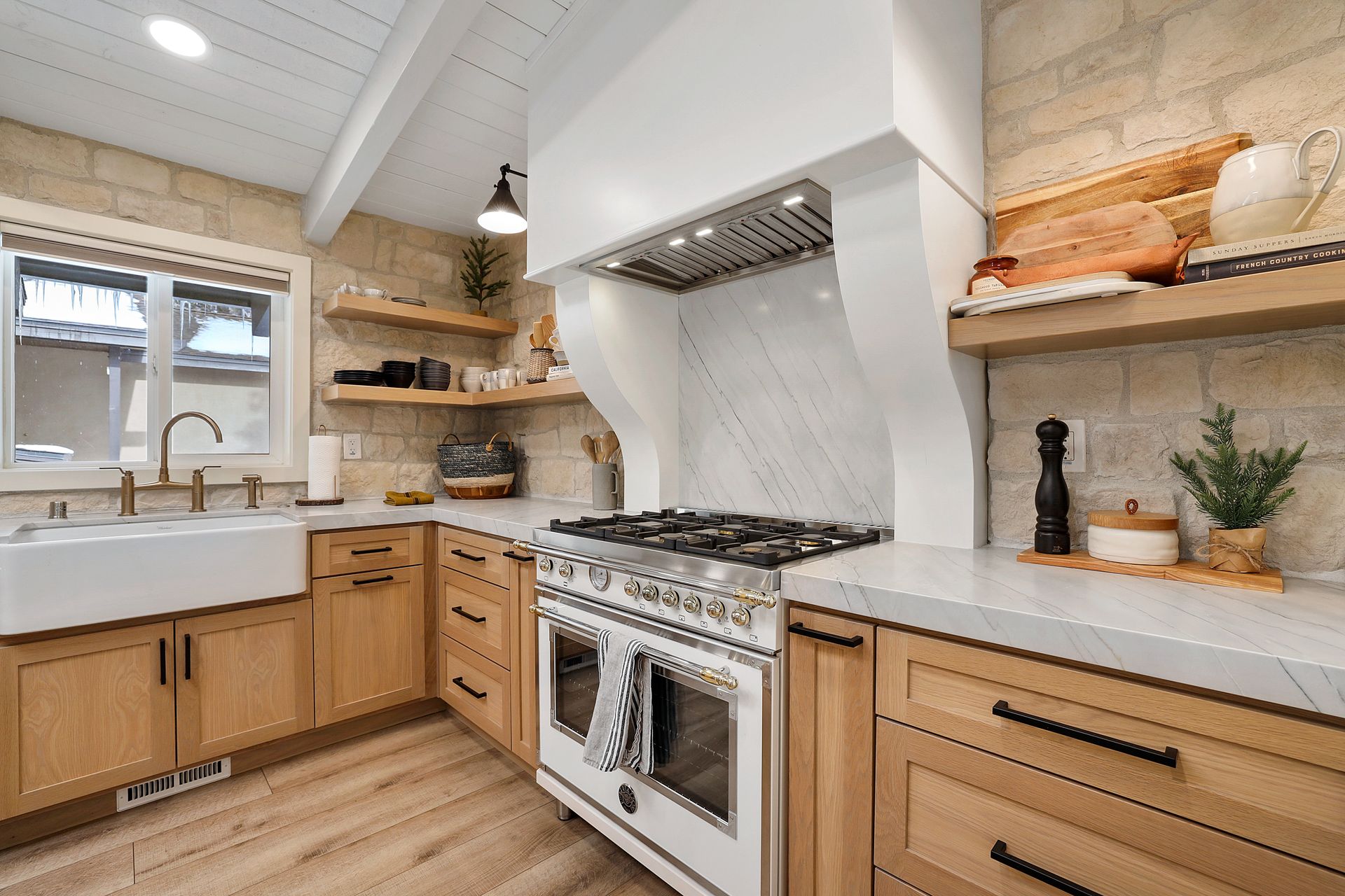 Bright modern kitchen with wooden cabinets, white countertops, gas stove, and farmhouse sink