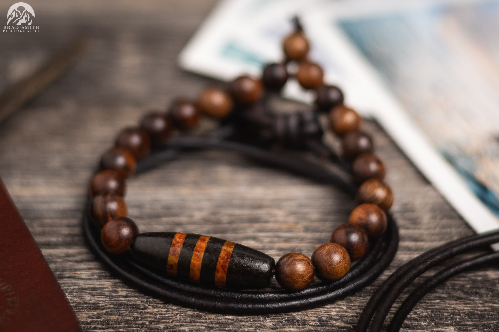 Wooden beaded bracelet with black and orange accents on a rustic wooden surface