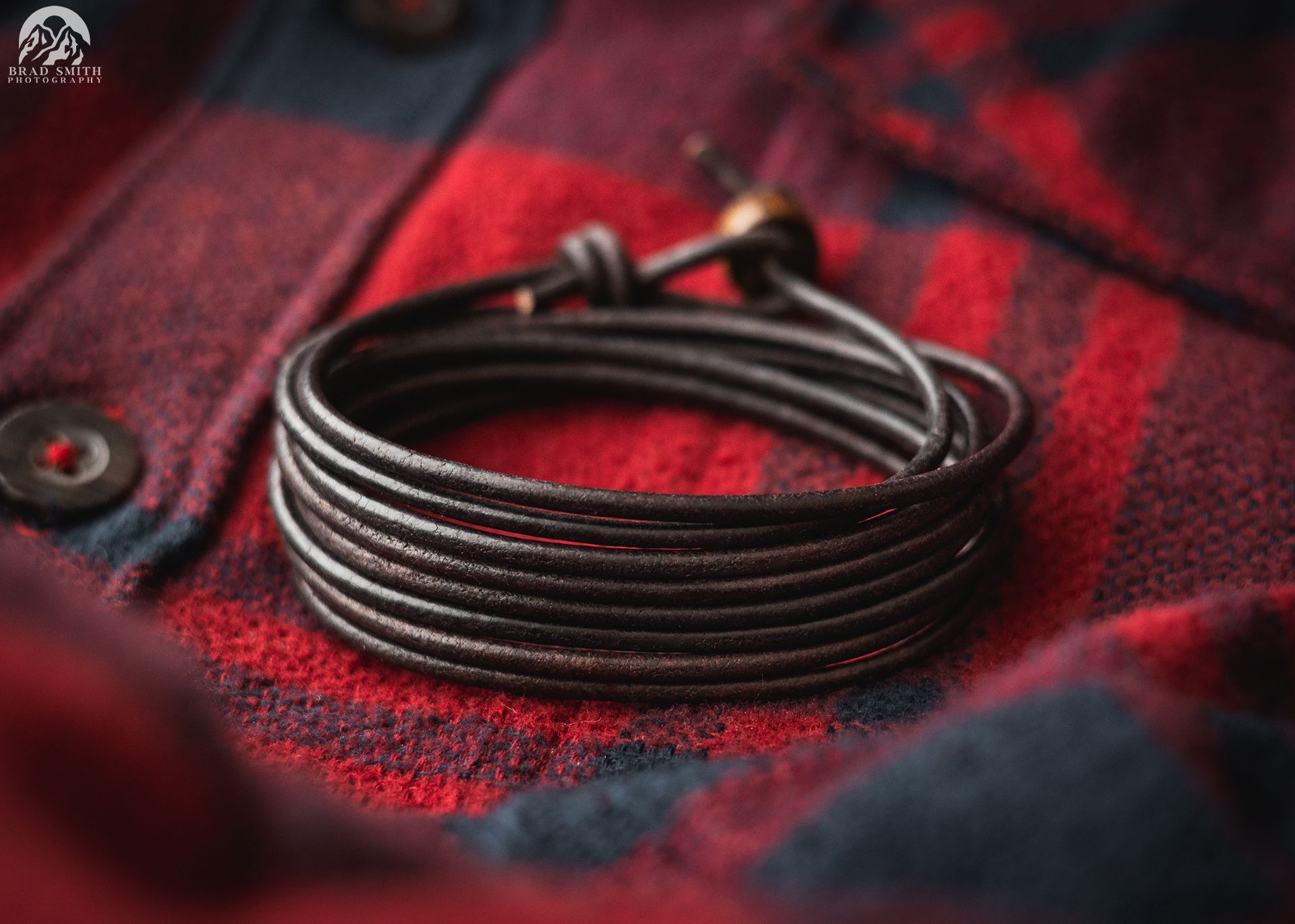 Coiled black cable resting on a red-and-black plaid fabric surface
