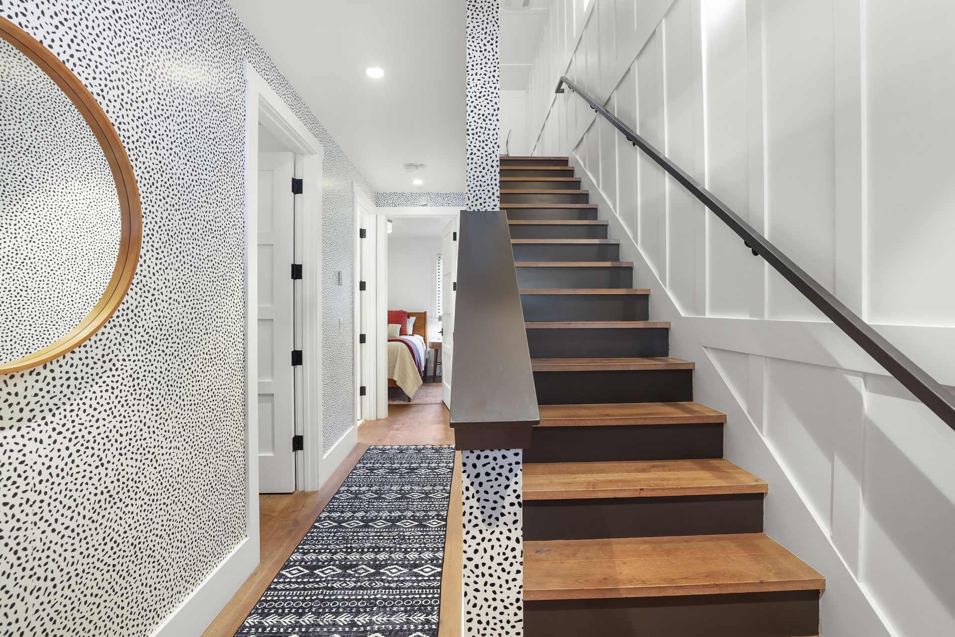 Bright hallway with patterned wallpaper, staircase, and wooden steps leading upstairs