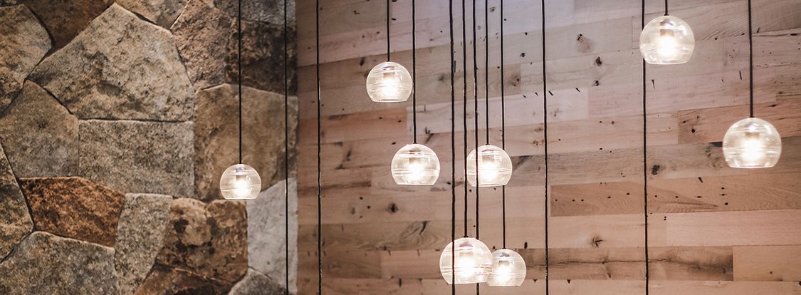 Hanging globe pendant lights over a stone and wood wall in a rustic interior