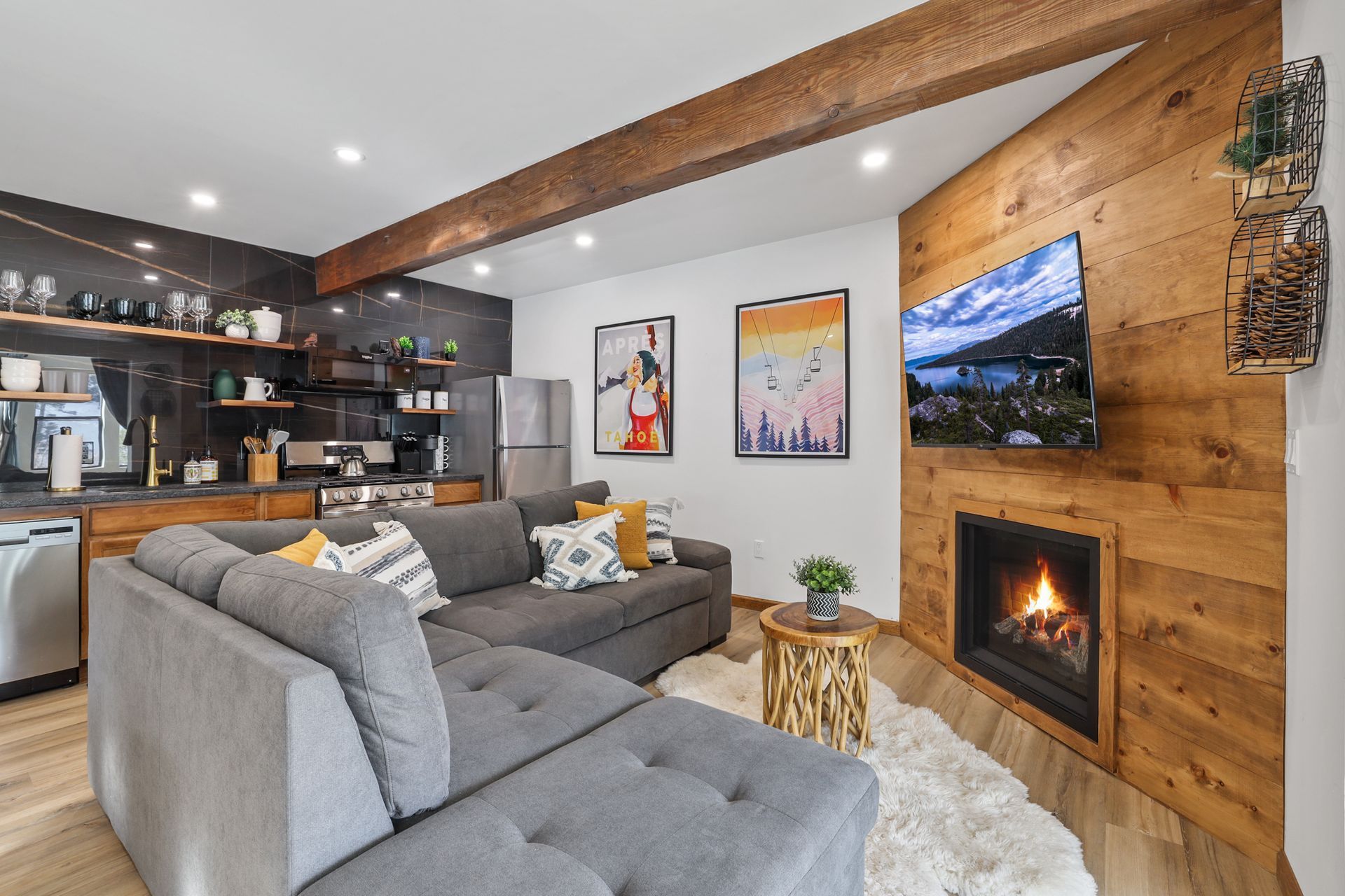 Modern living room with gray sectional, wood accent wall, fireplace, and wall-mounted TV