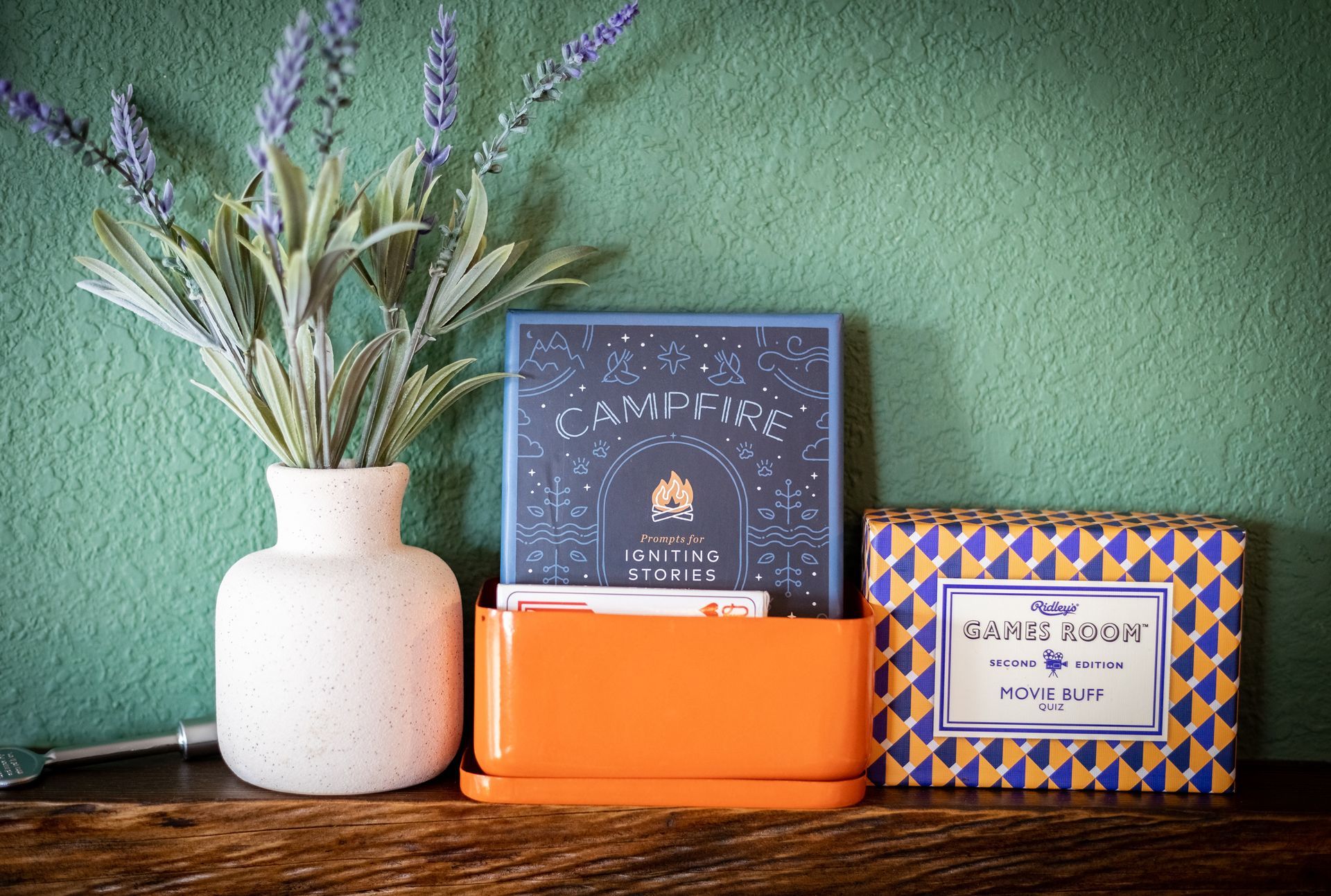 Candles and a potted plant on a wooden shelf against a green wall