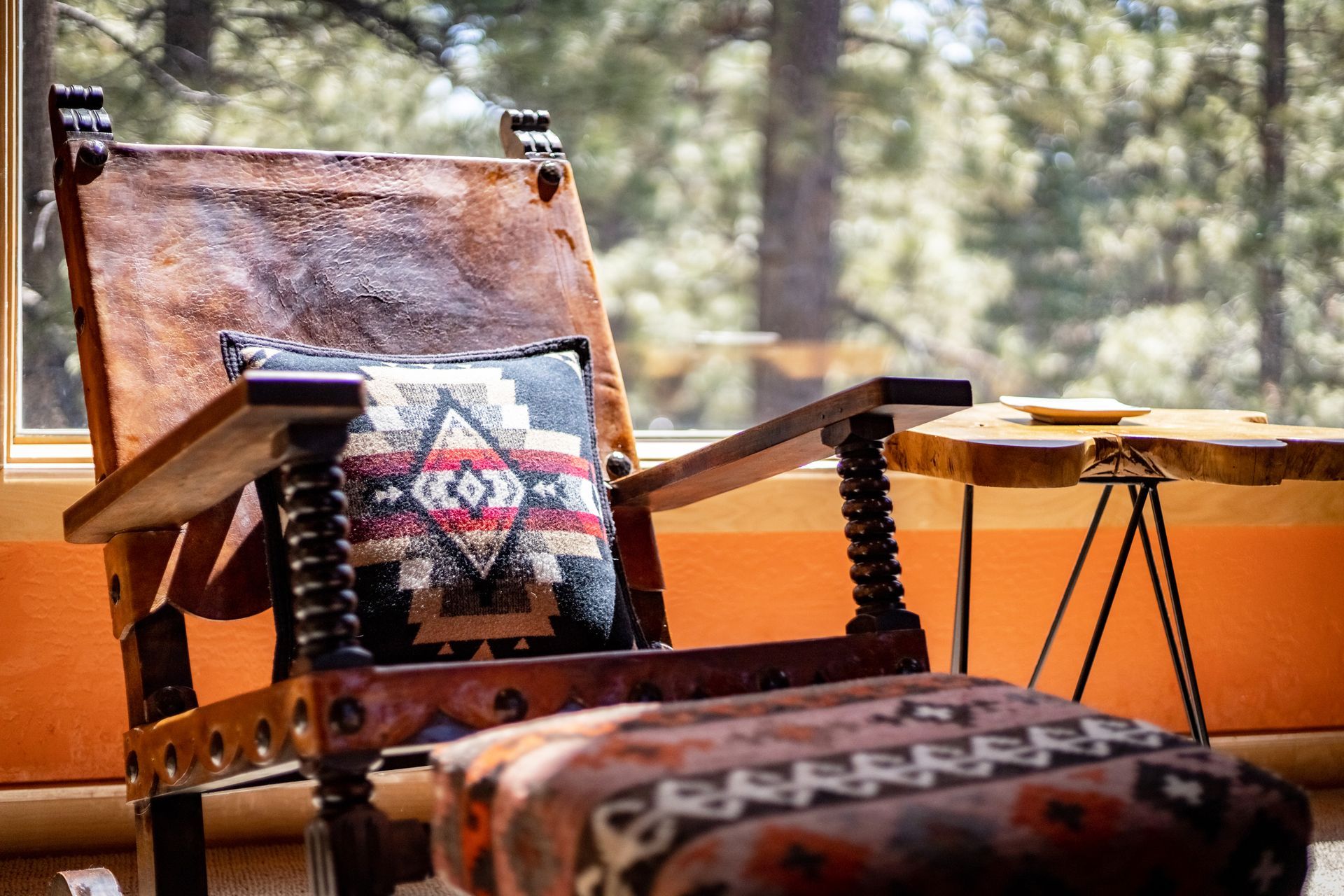 Rustic chair with a patterned cushion on an orange patio, outdoors against a wooded background