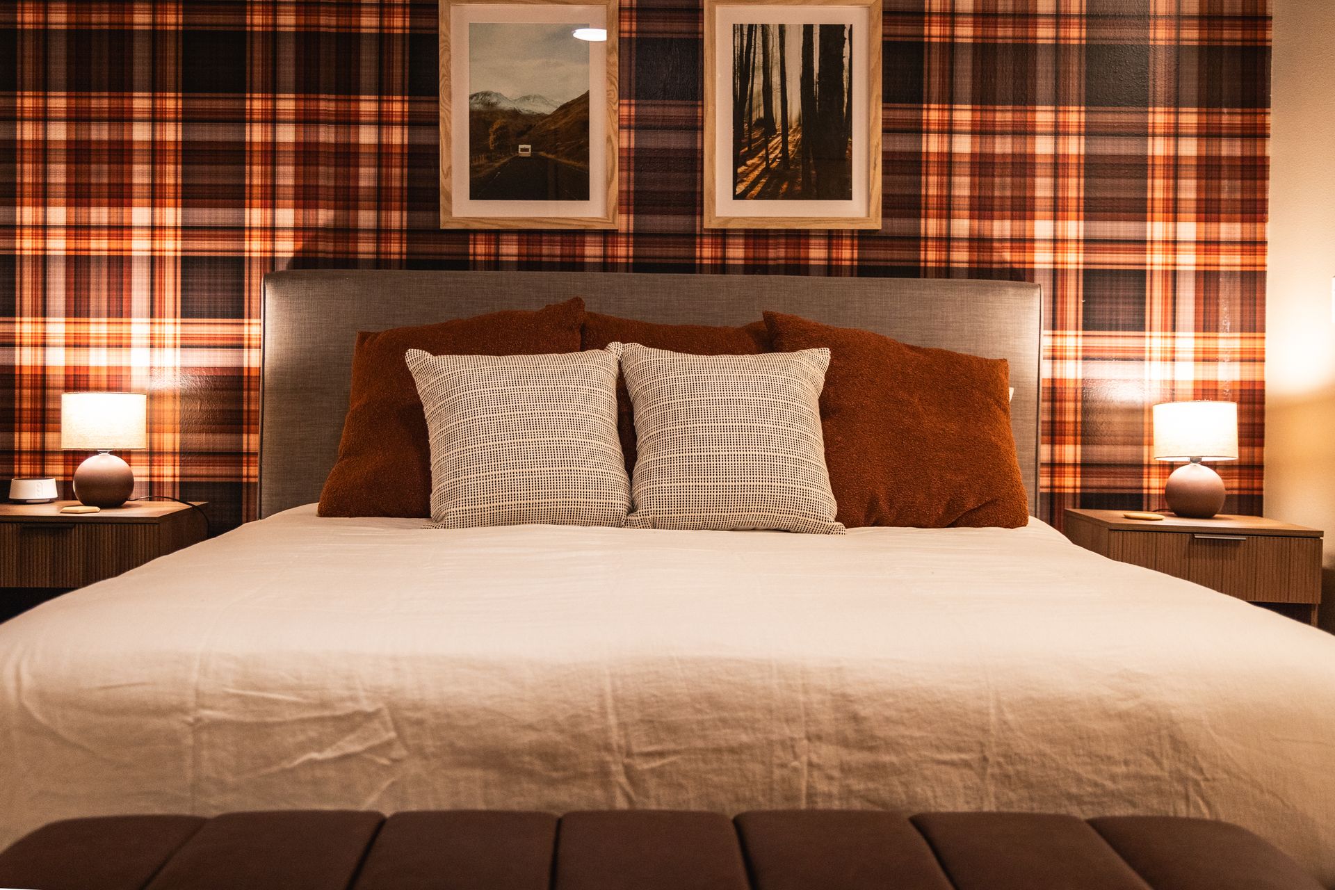 Cozy bedroom with a large bed, plaid wallpaper, bedside lamps, and framed artwork above the headboard