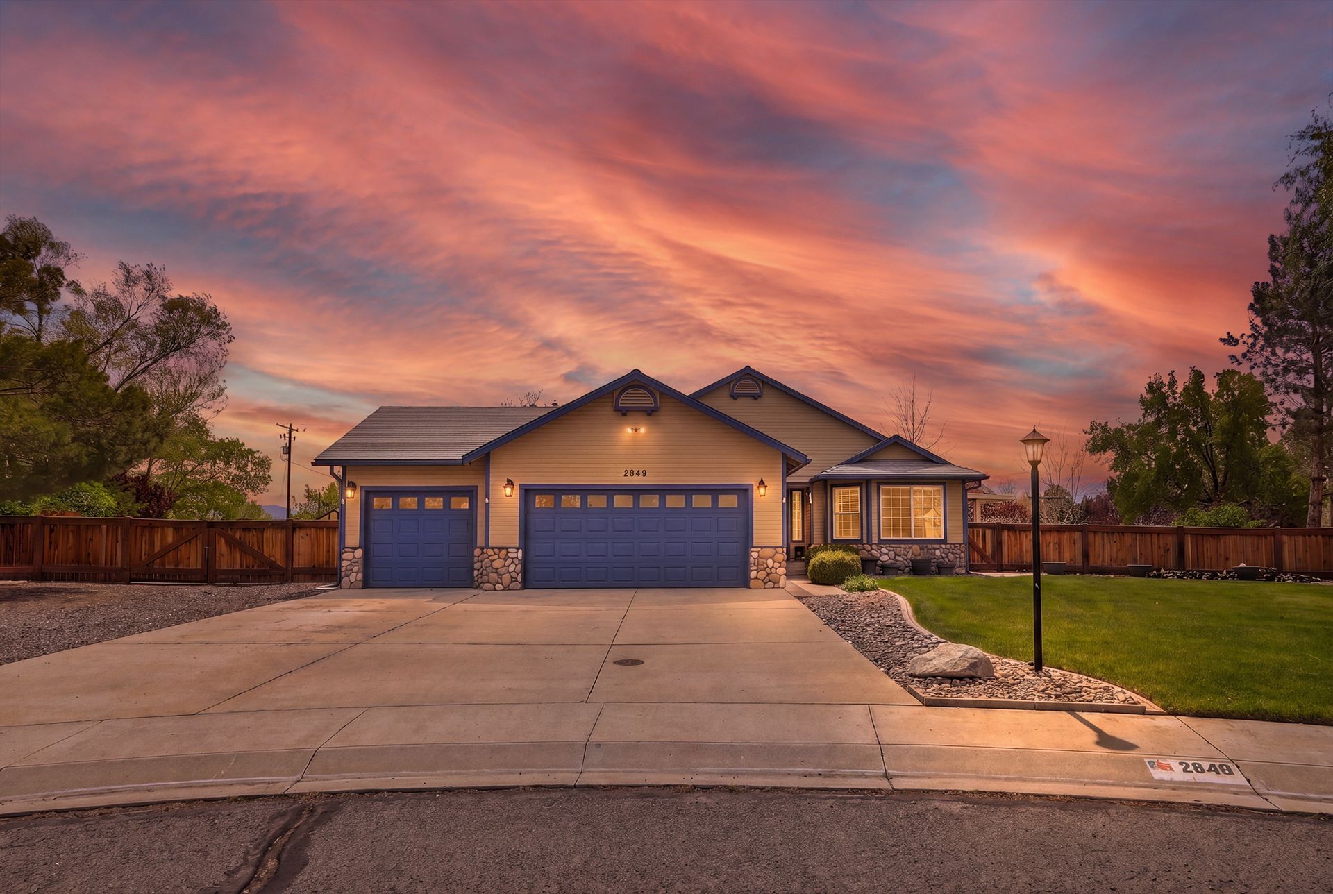 Single-story house with three-car garage at sunset, pink sky over a landscaped suburban street