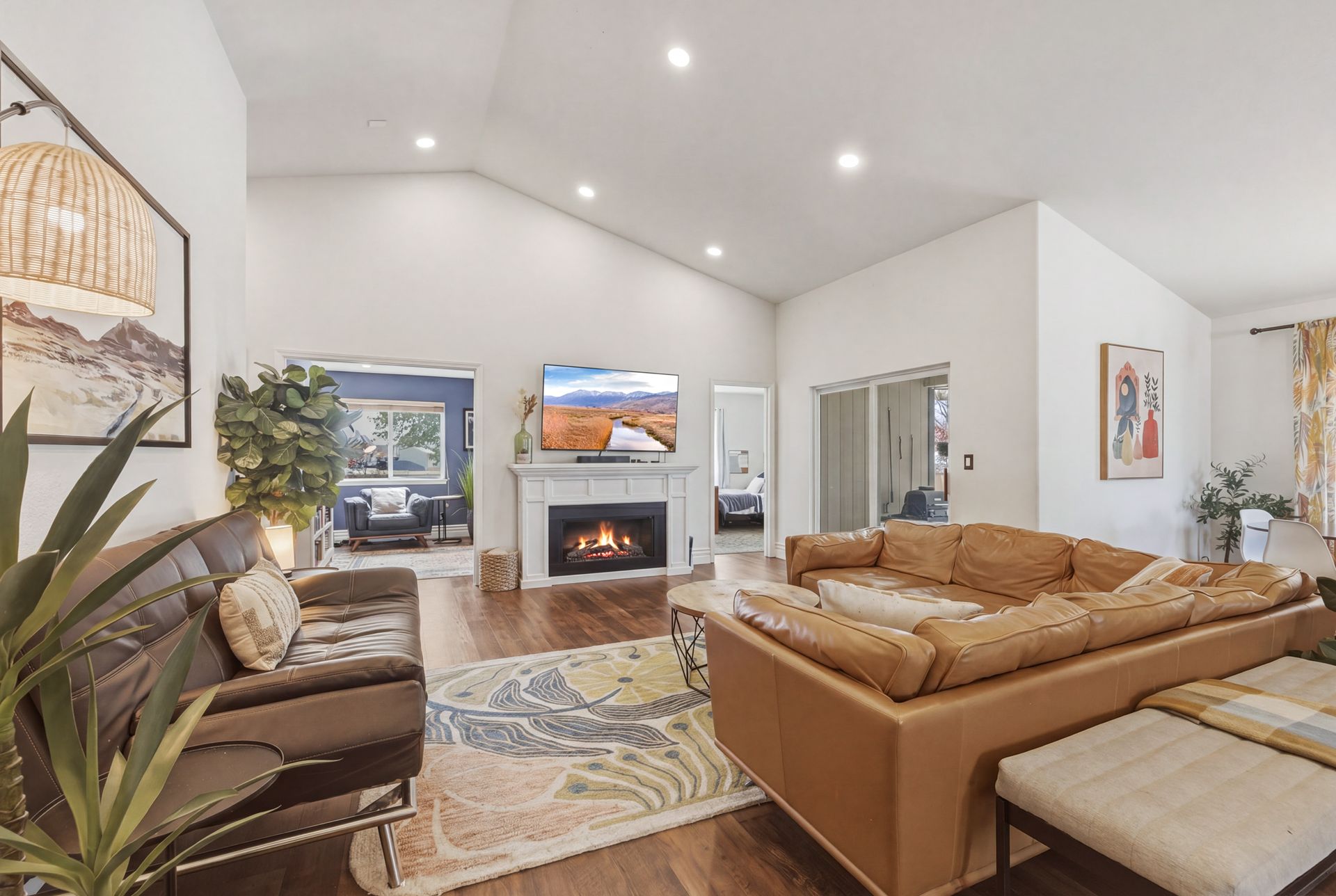 Bright modern living room with tan sectional, fireplace, skylights, and large windows