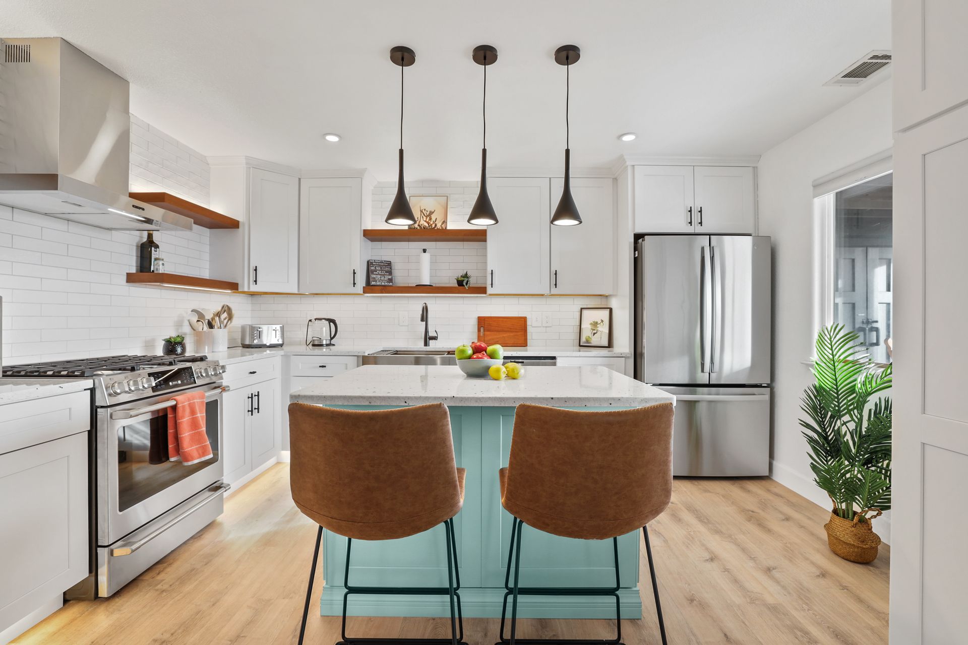 Bright modern kitchen with white cabinets, island, stainless-steel appliances, and three pendant lights