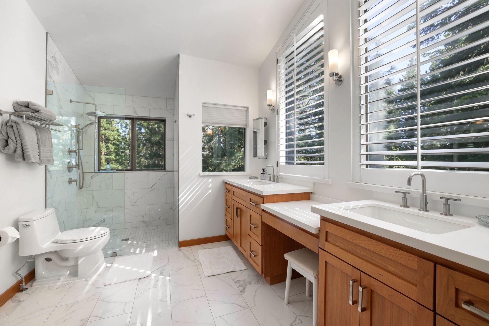 Bright modern bathroom with double vanity, walk-in shower, and large windows