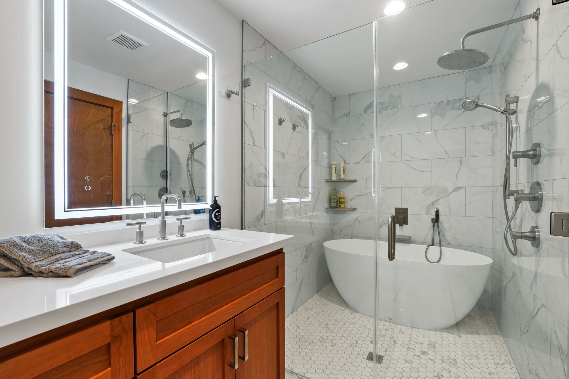 Modern marble bathroom with double vanity, round soaking tub, glass shower, and mirrored wall.