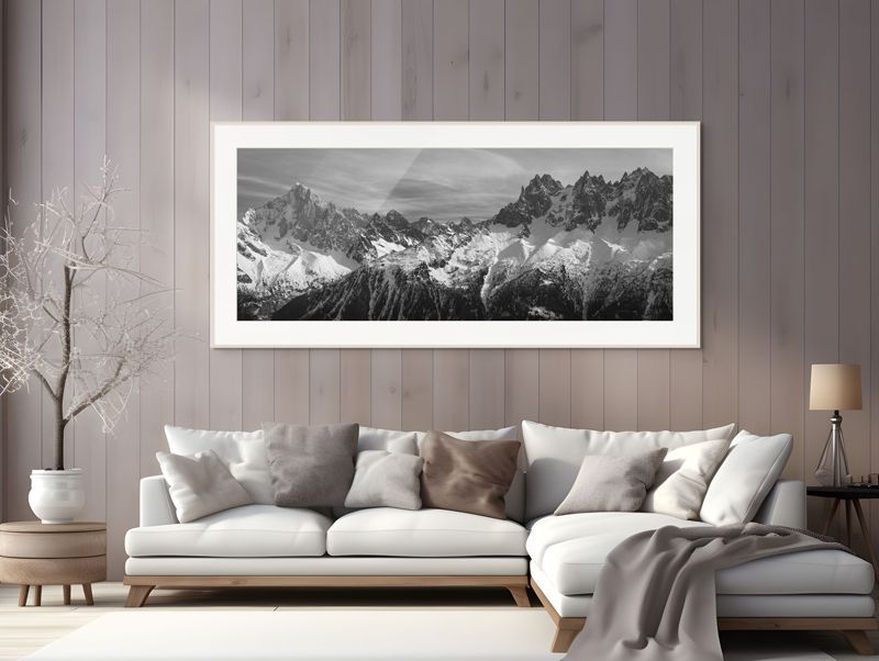 Minimalist living room with a beige sectional, neutral decor, and a large black-and-white mountain landscape above it