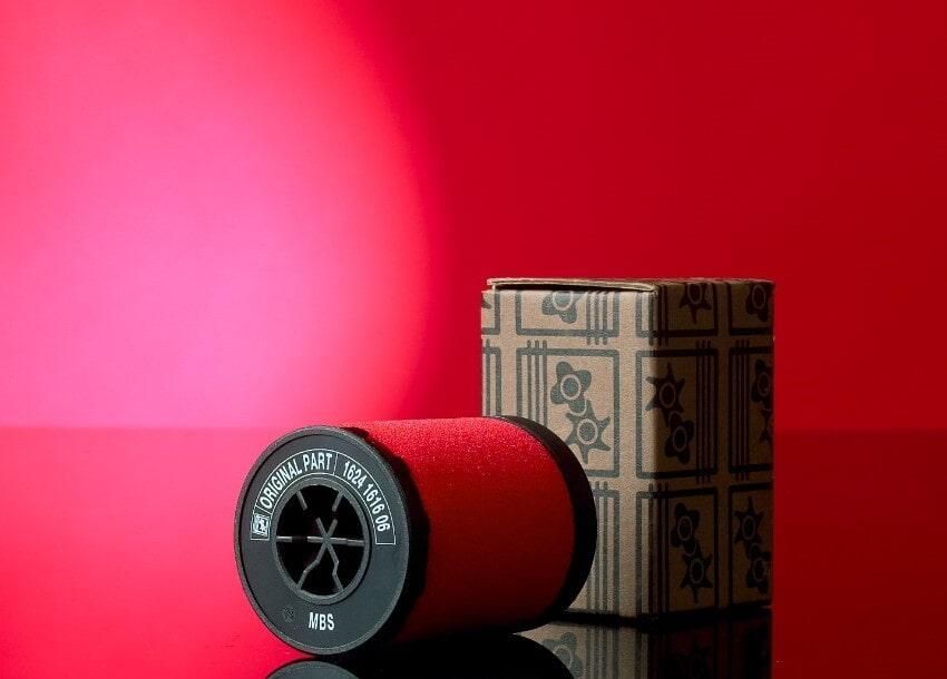 Un carrete de hilo rojo se encuentra al lado de una caja sobre una mesa.