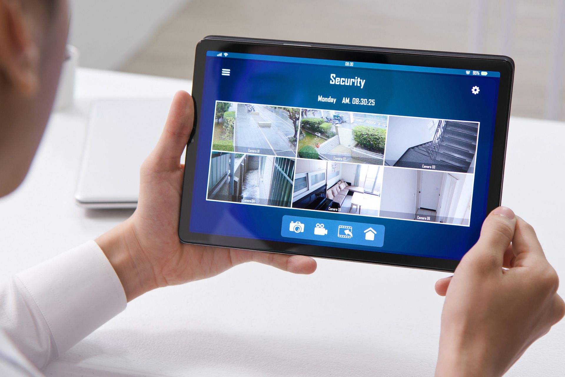 Homeowner at work holding a tablet checking on their home security system