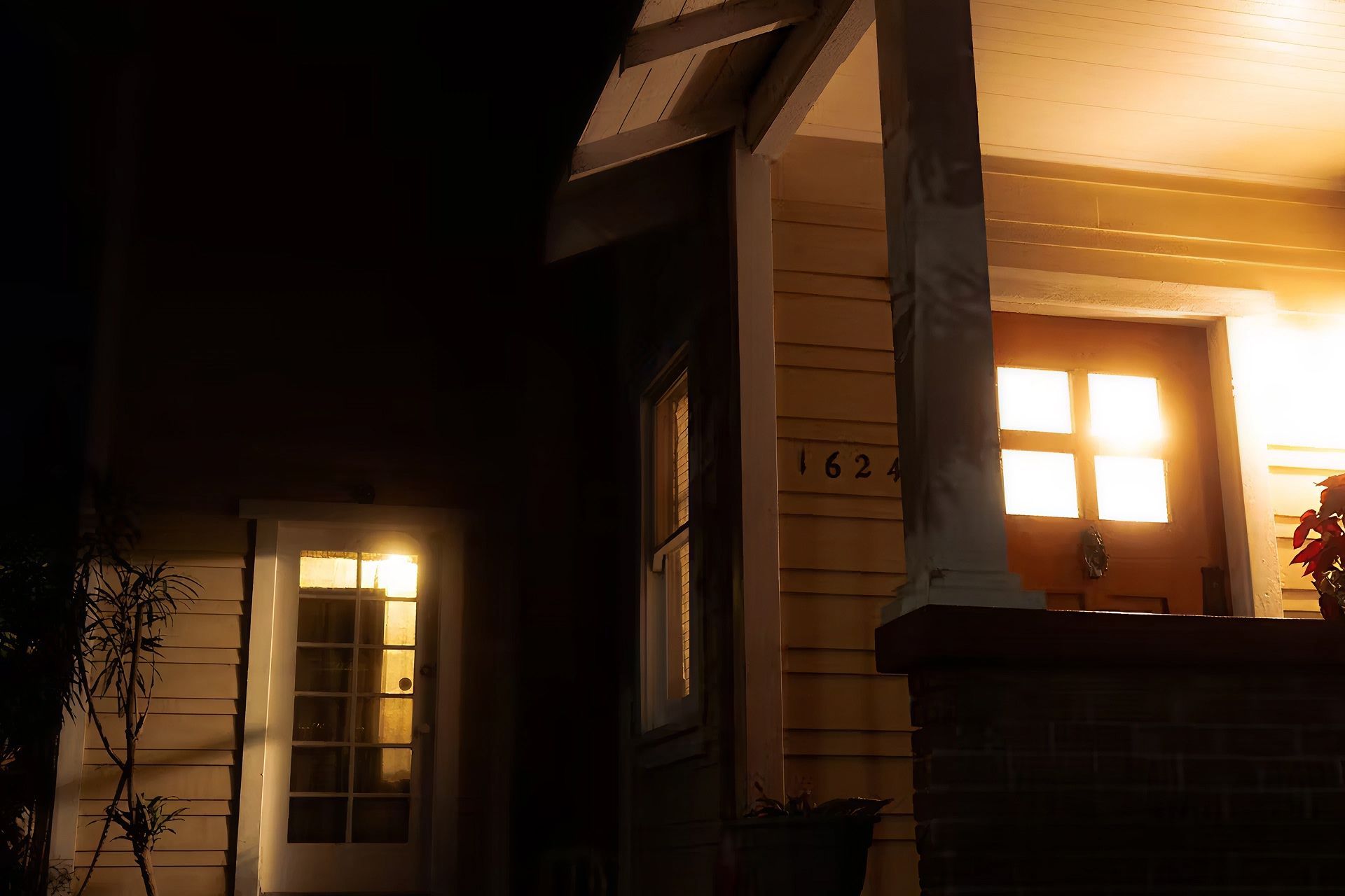 A nighttime shot of a house’s front porch glowing with soft yellow light.