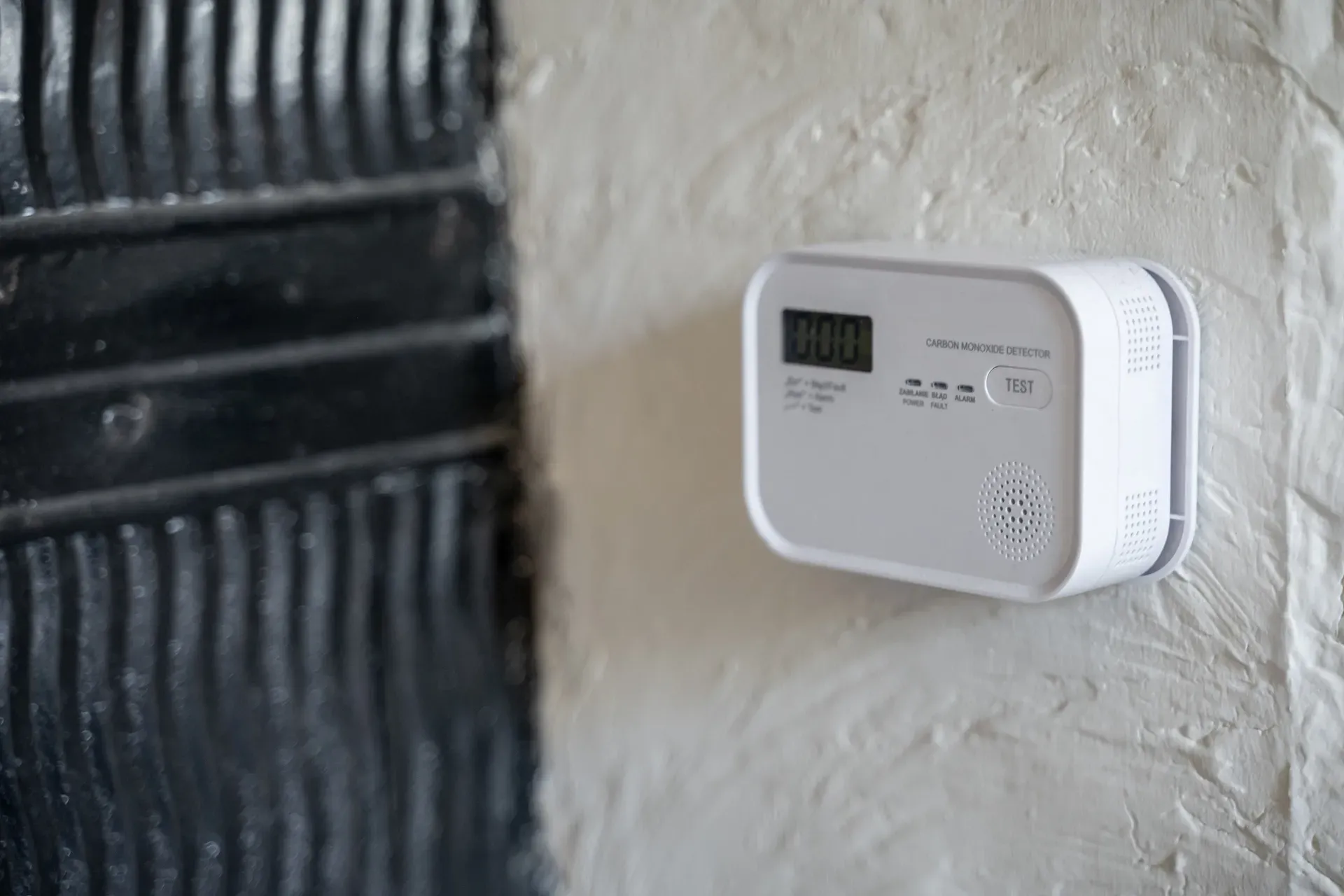 A carbon monoxide detector mounted on a wall near a stove.