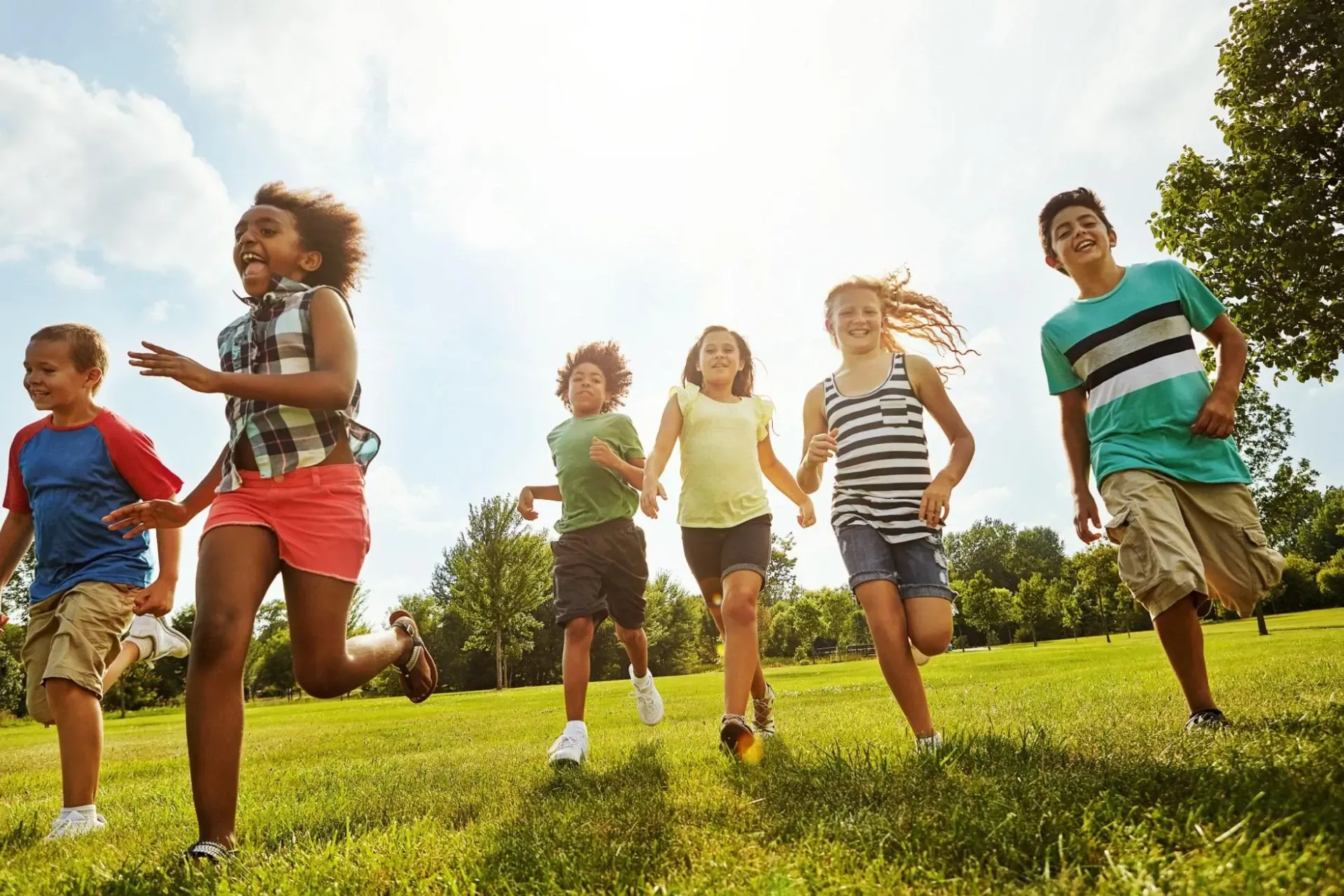Kids running in a sunny park in the Burlington neighbourhood on a summer day.