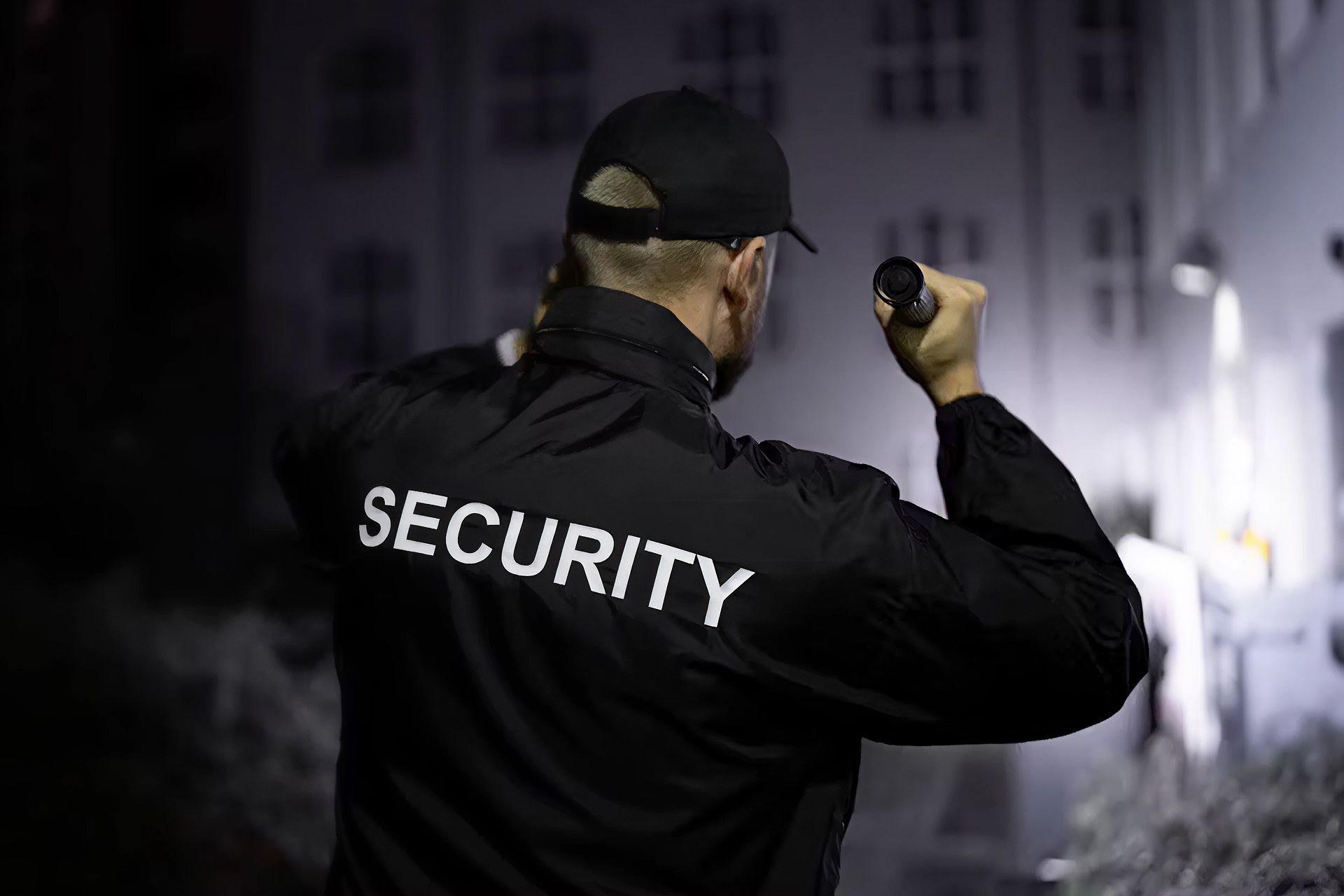 A security guard shines a flashlight while inspecting a courtyard