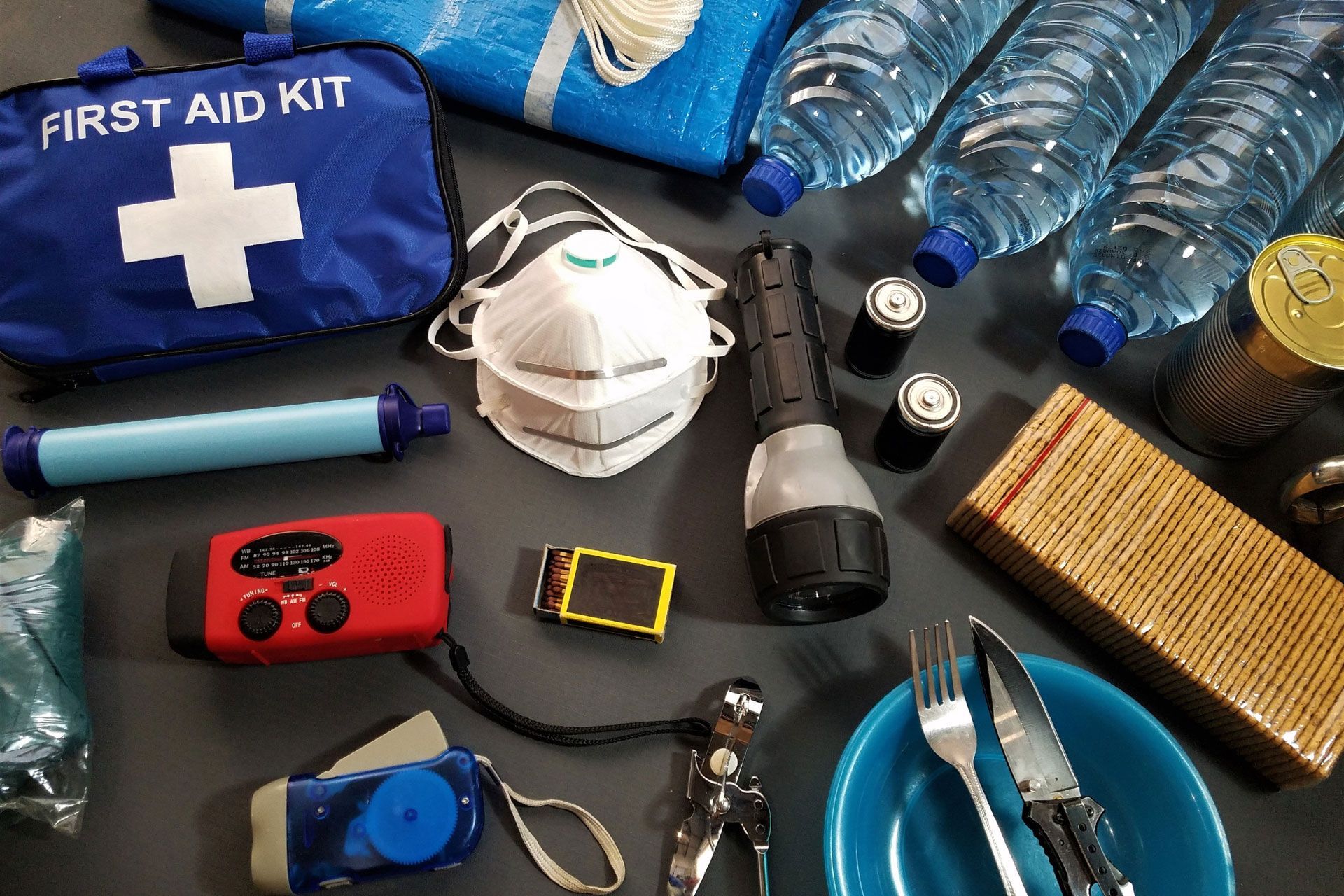 The contents of a first aid and disaster kit sitting out on a black table