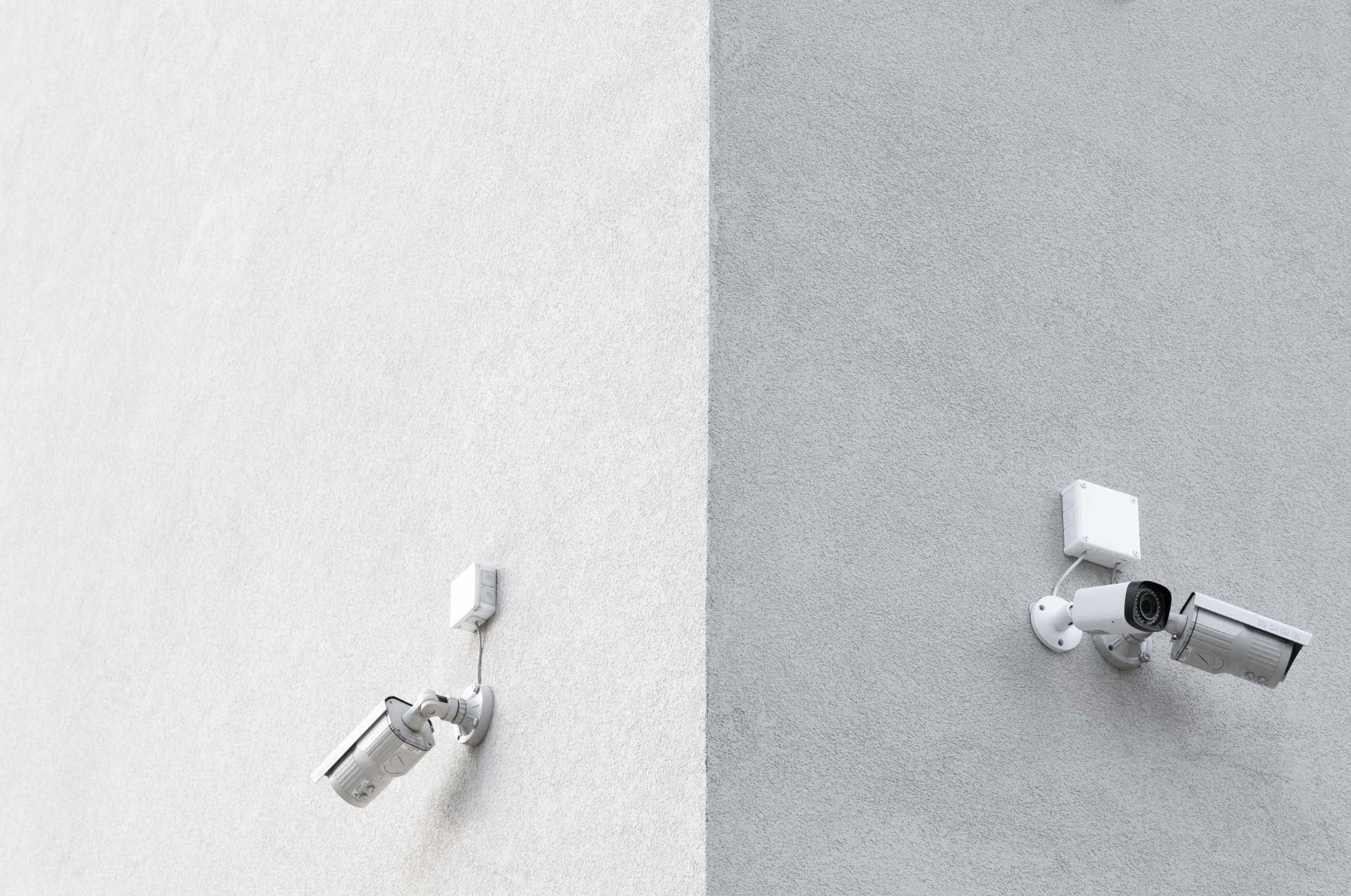 Two security cameras on a white exterior building corner