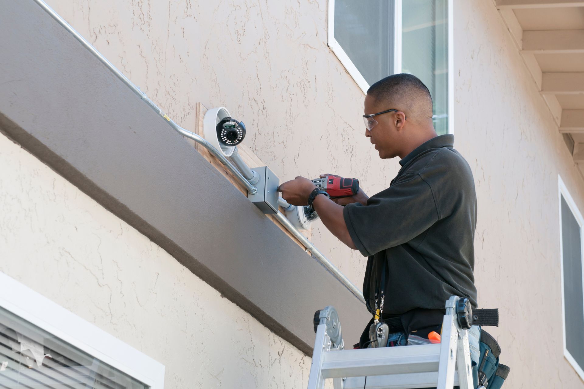 A technician installs a security camera securely on a home’s exterior wall
