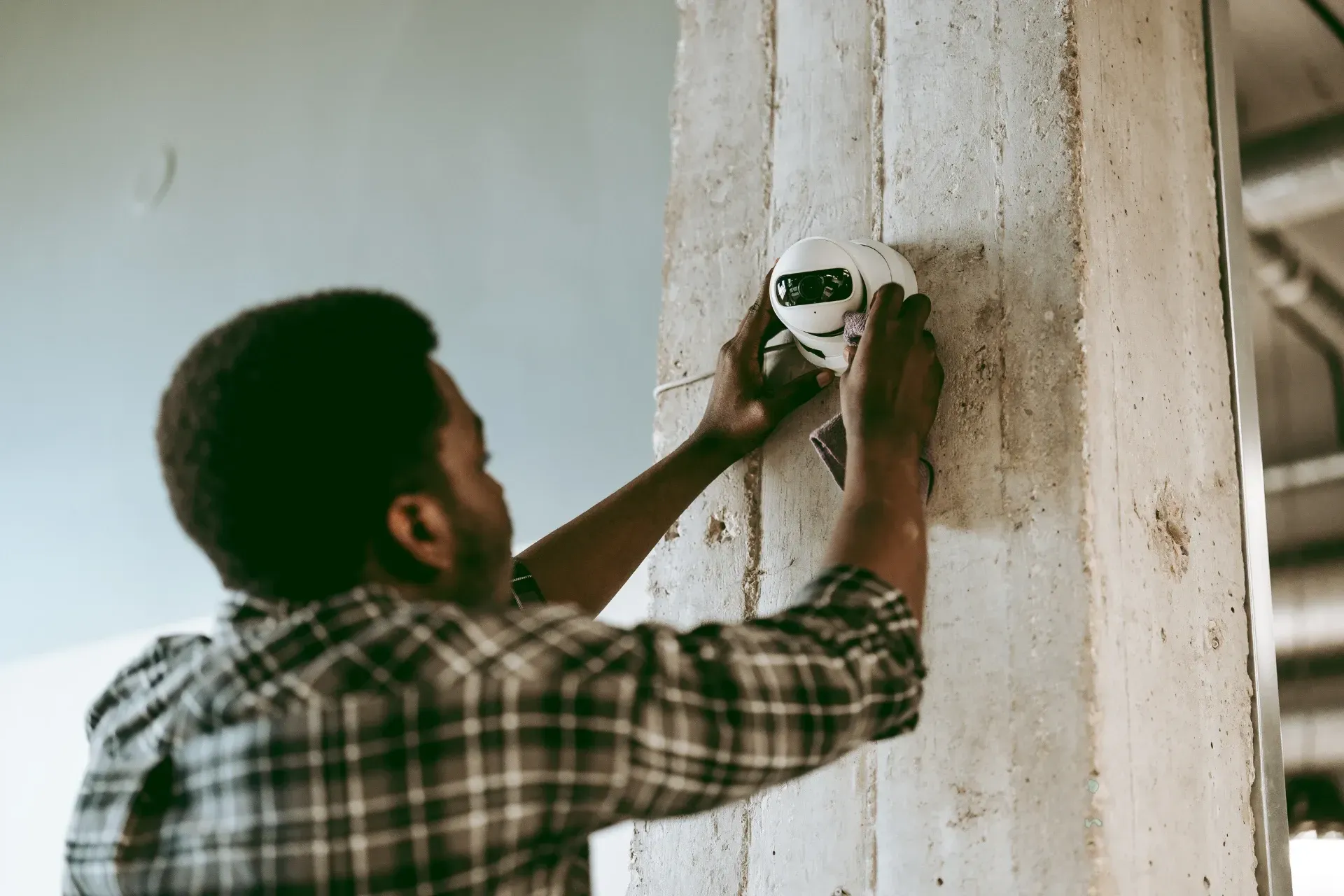 A man installing a security camera on a wall