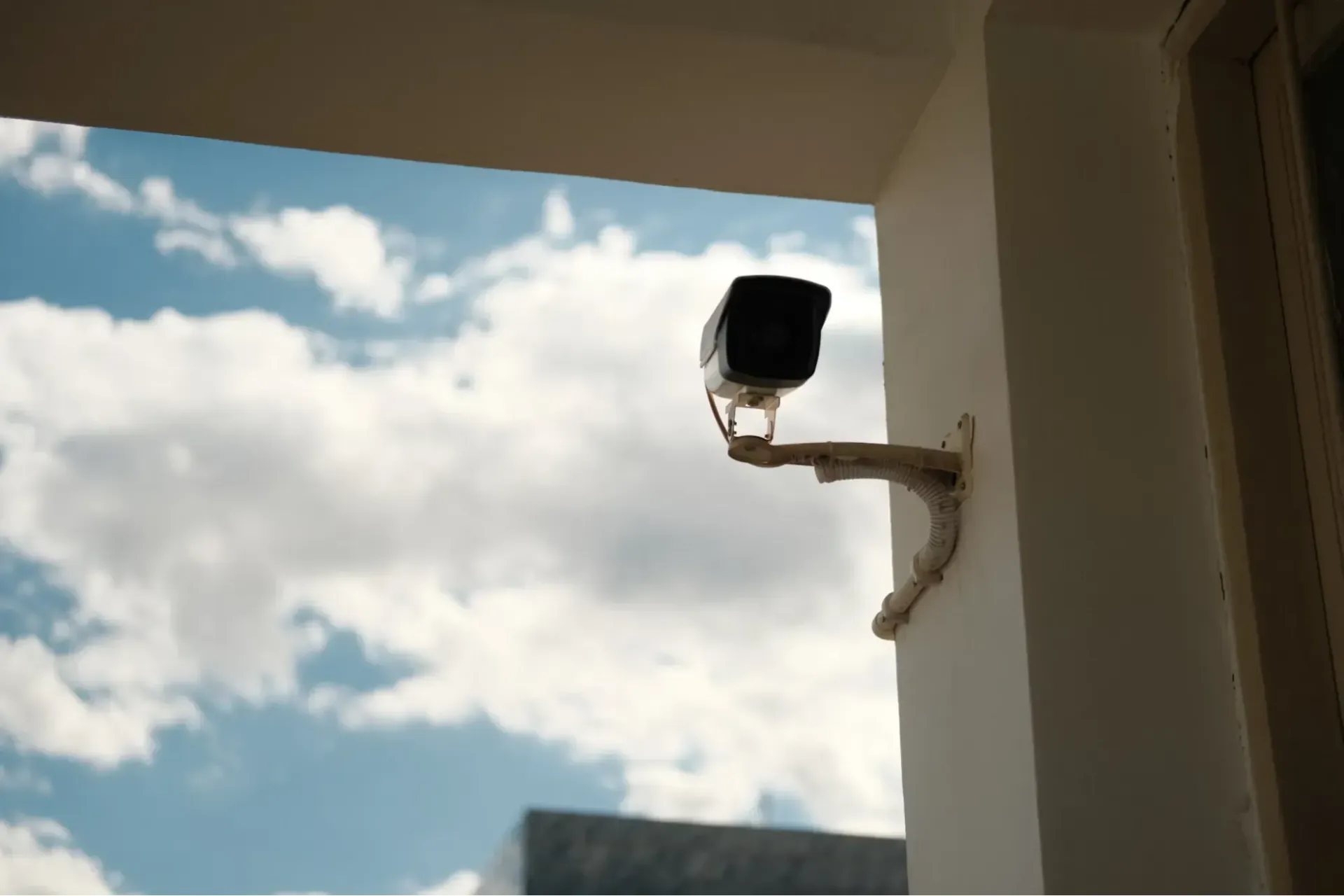 A security camera mounted on a stucco house wall.