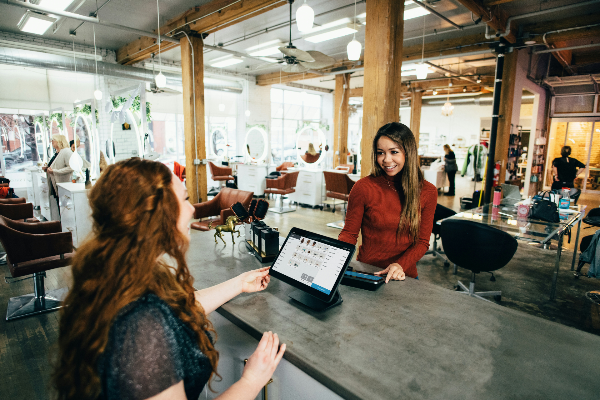 Two women chatting at the reception desk of a hair salon