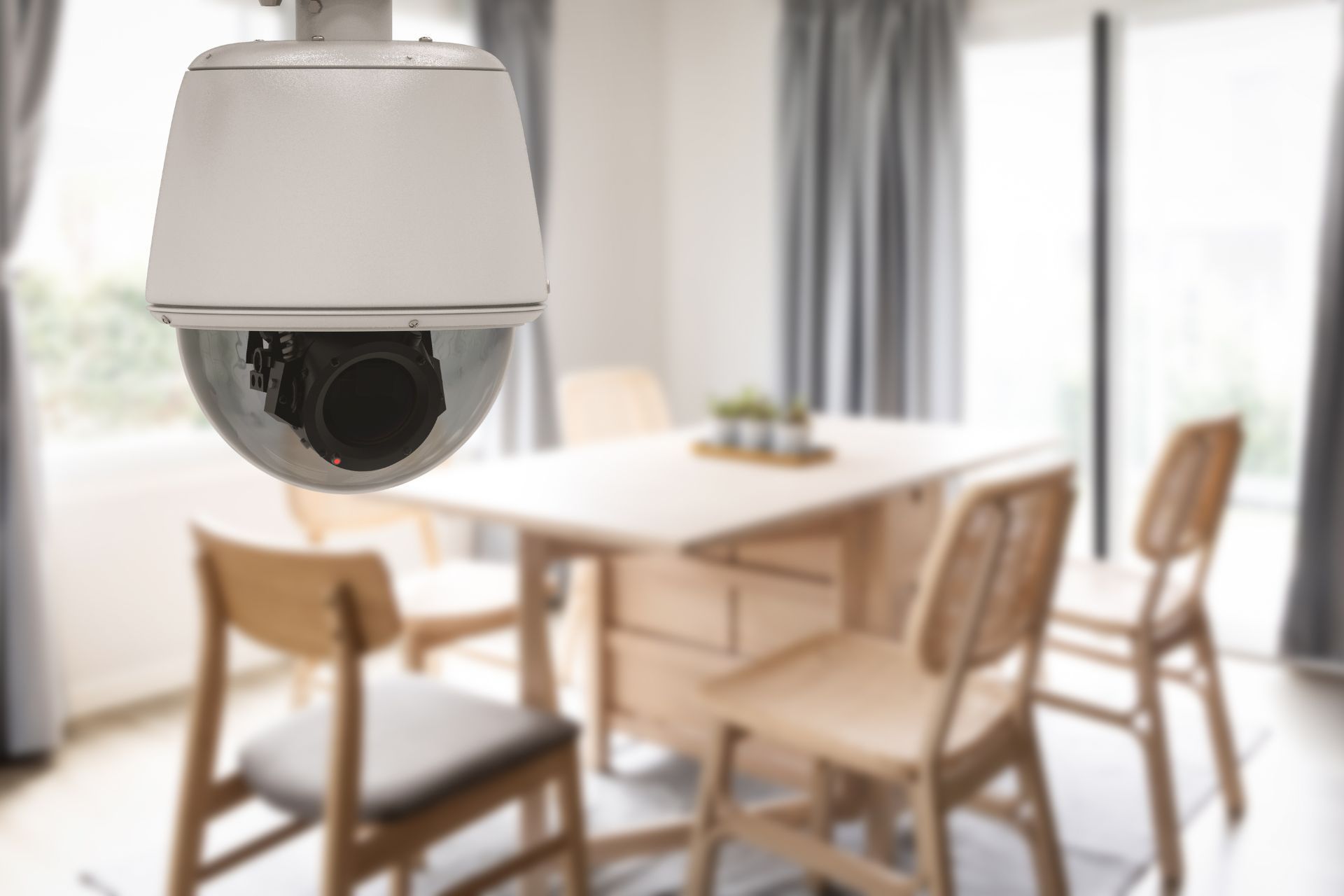 An indoor security camera installed within the dining room of a home