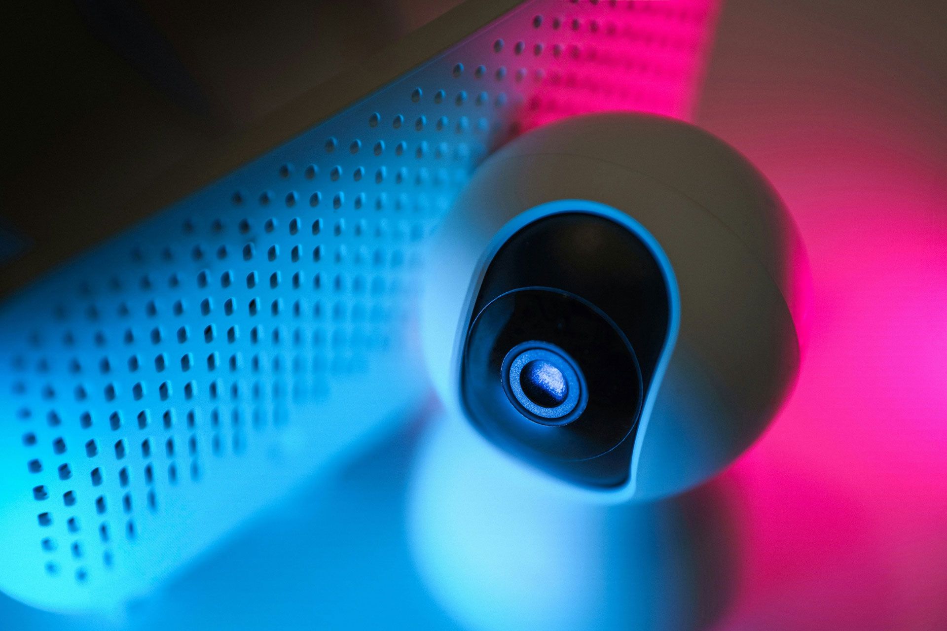 A security camera and speaker in front of a colourful background