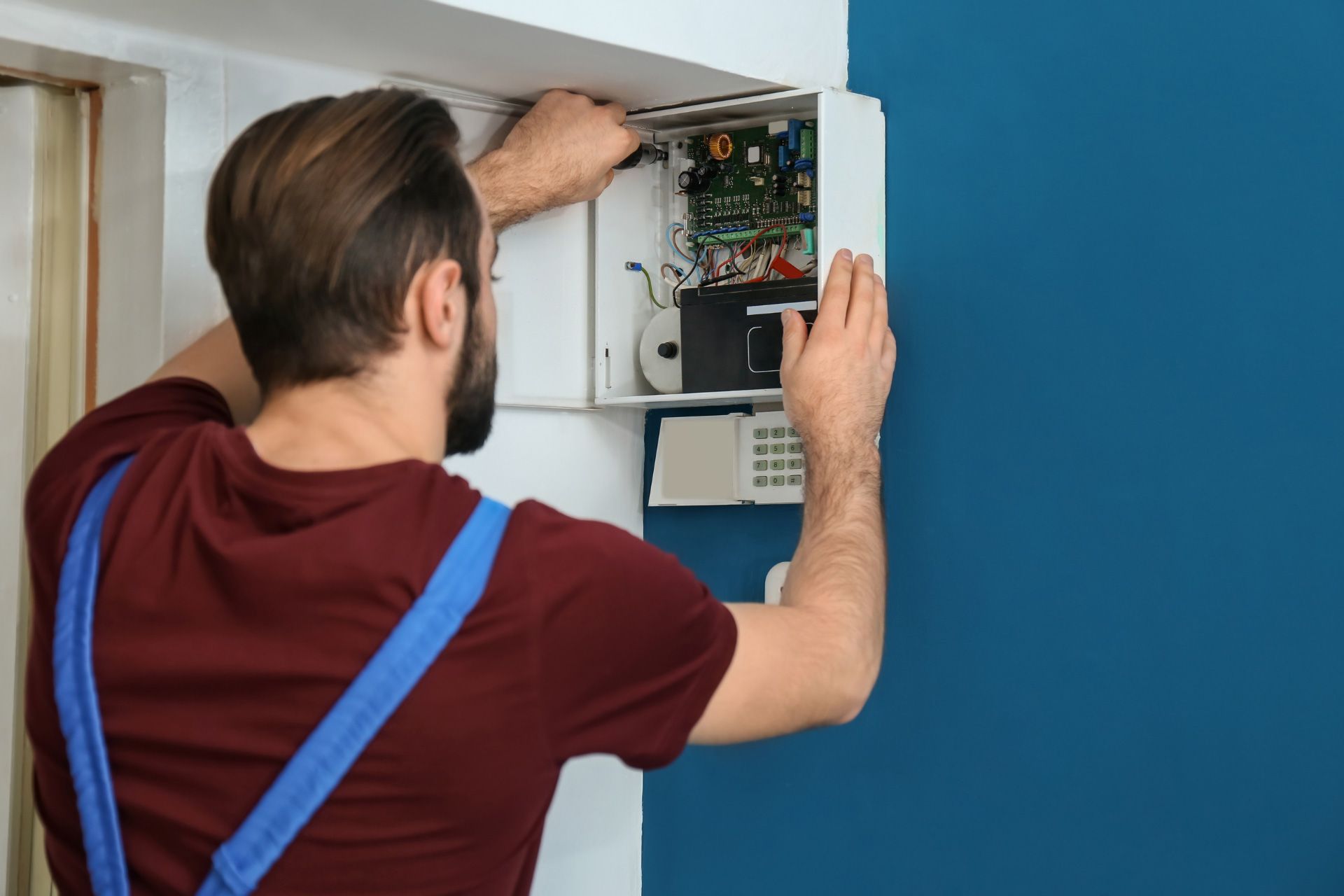 Professional installing a security system to a blue wall