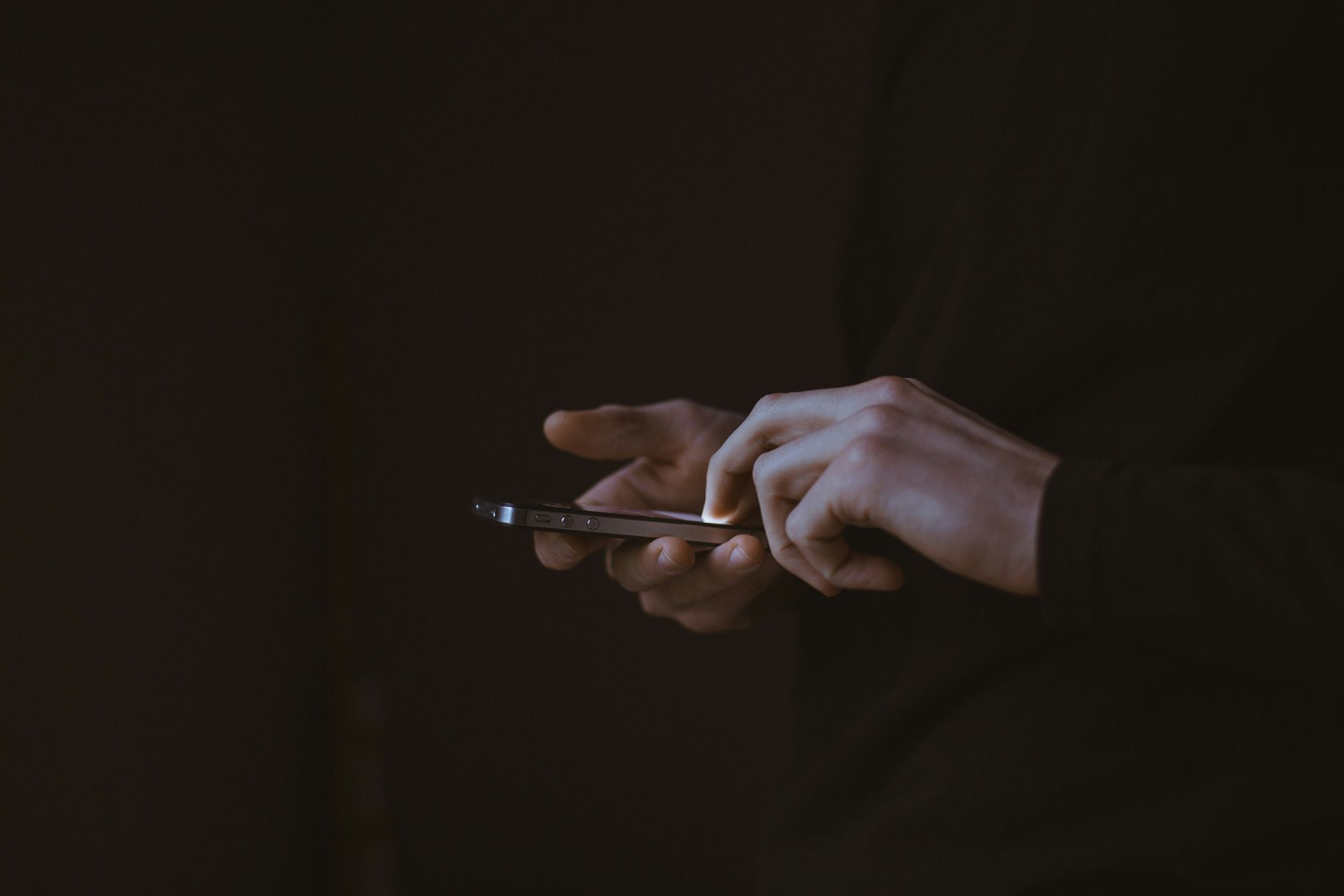 a person using their phone in front of a black backdrop