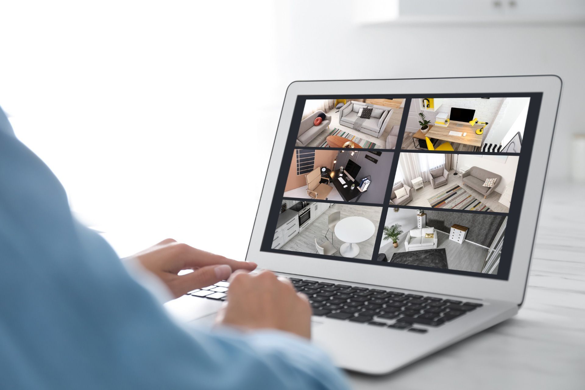 A person uses a laptop to check their home’s self monitoring security system