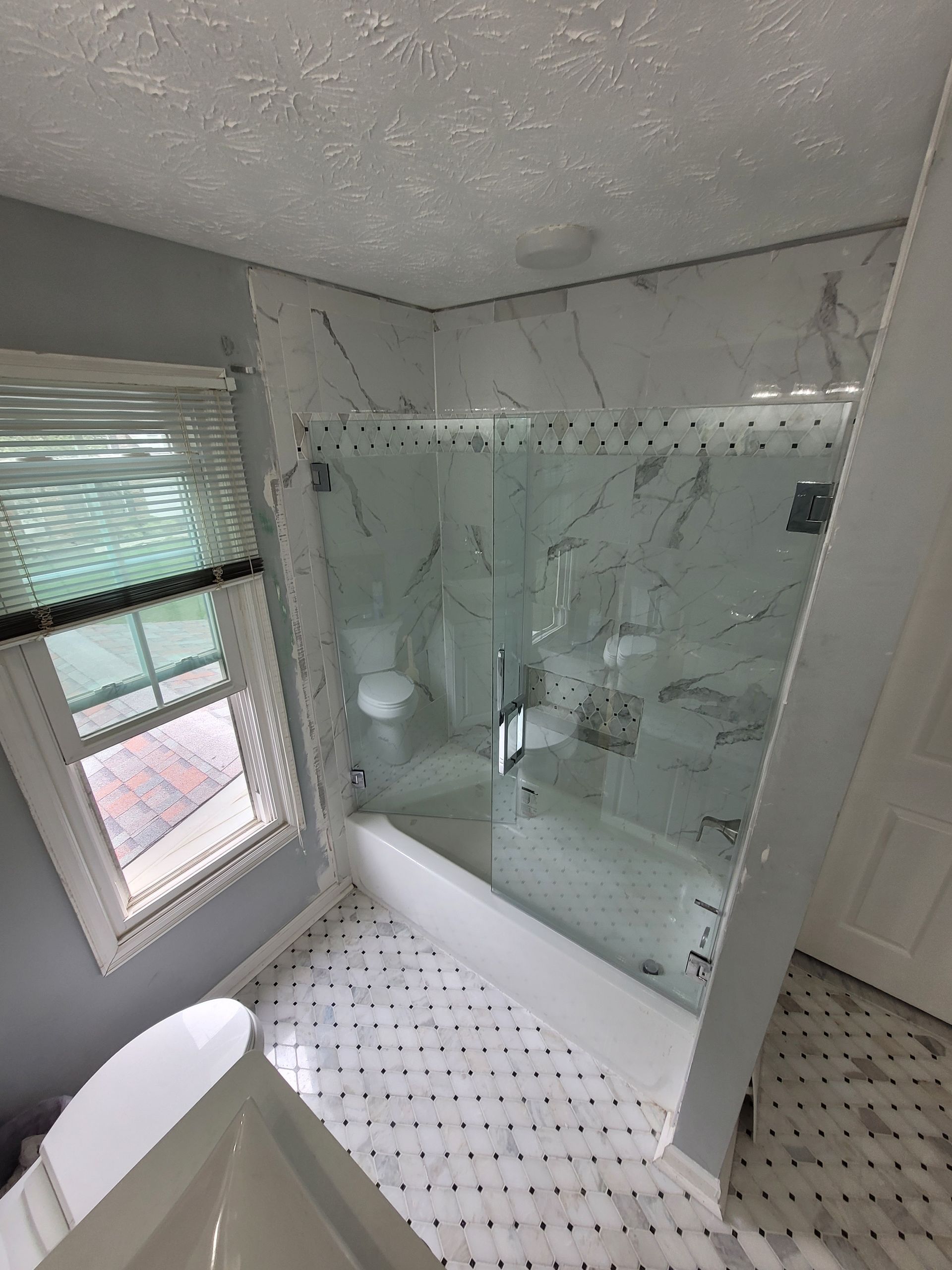 A bathroom with a tub , toilet , shower and window.
