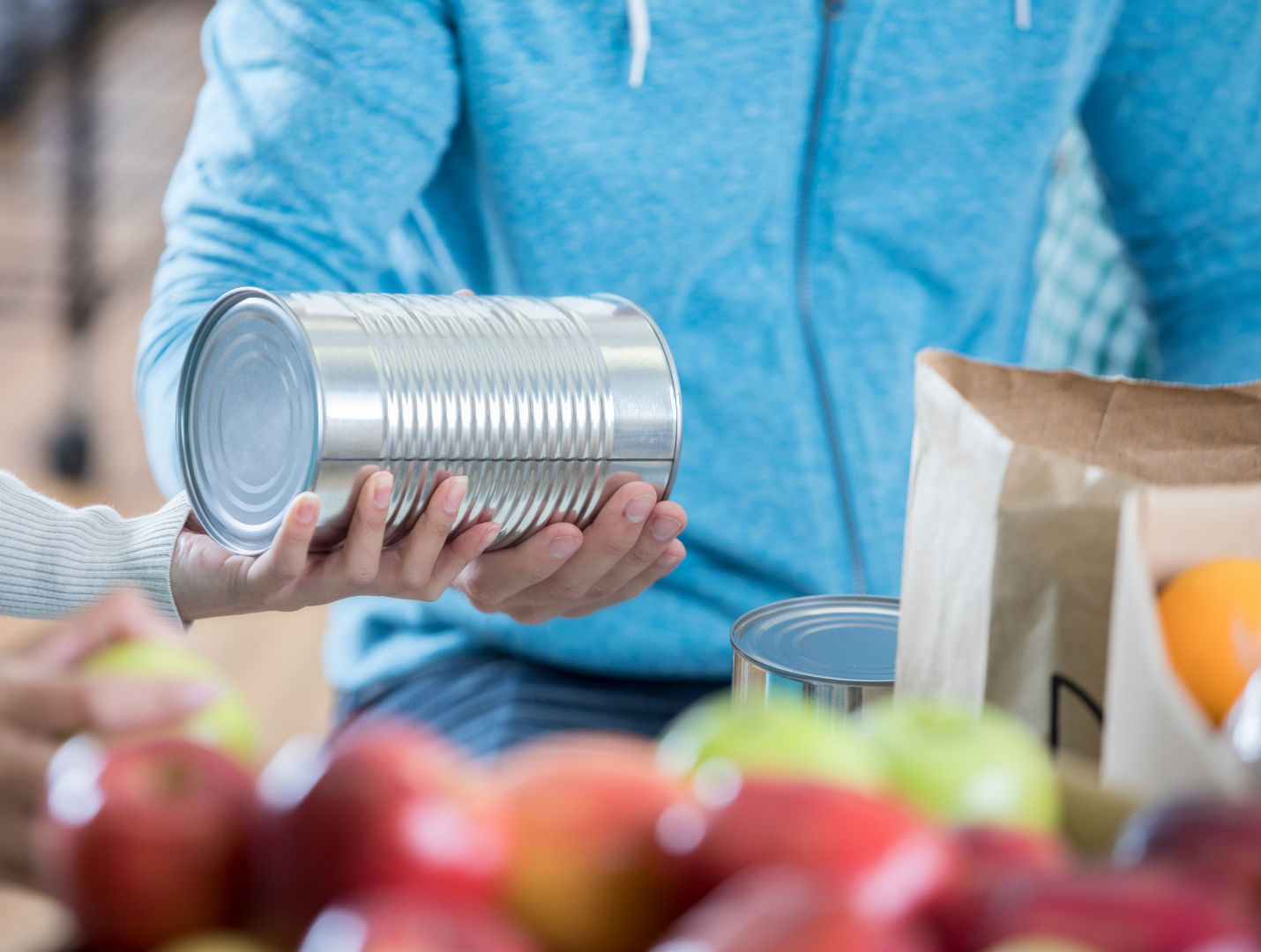 A person is handing a can of food to another person.