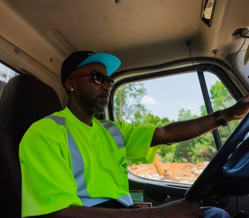 A man in a neon yellow shirt is driving a truck