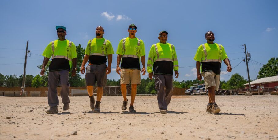 A group of men are walking in a line on a dirt road.