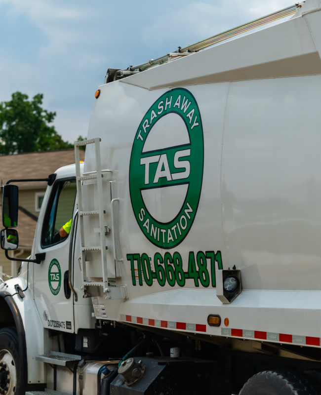 A trash away sanitation truck is parked in front of a house