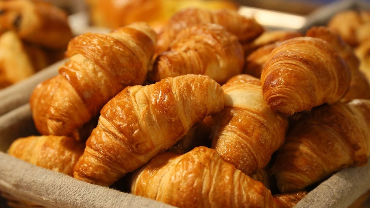 Basket filled with golden-brown croissants, a French pastry, ready to be enjoyed.