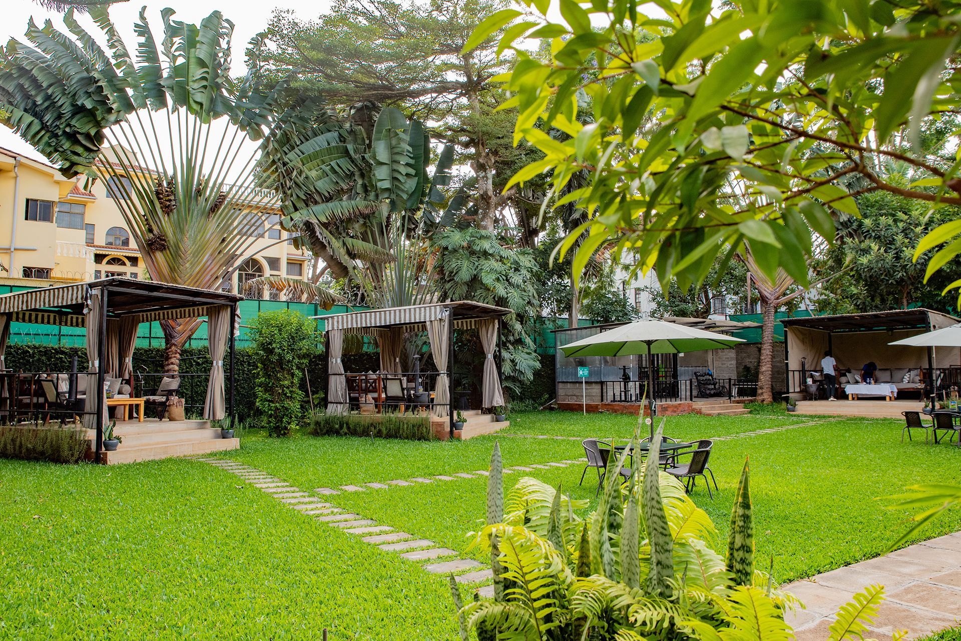 A lush green lawn with a few umbrellas in the background