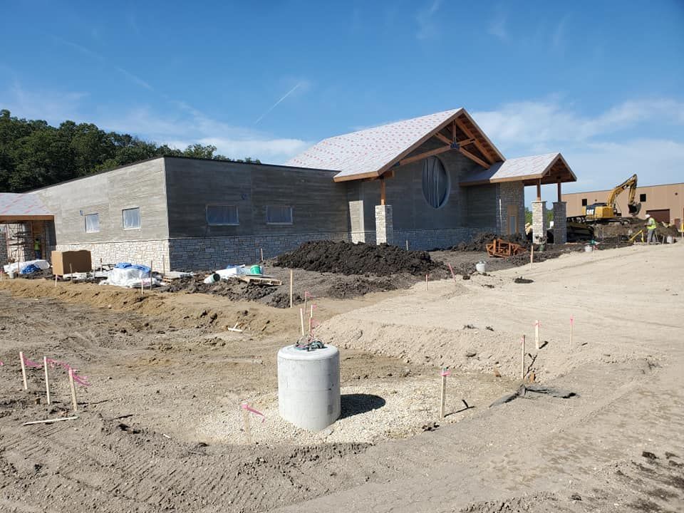 A large building is being built in the middle of a dirt field.