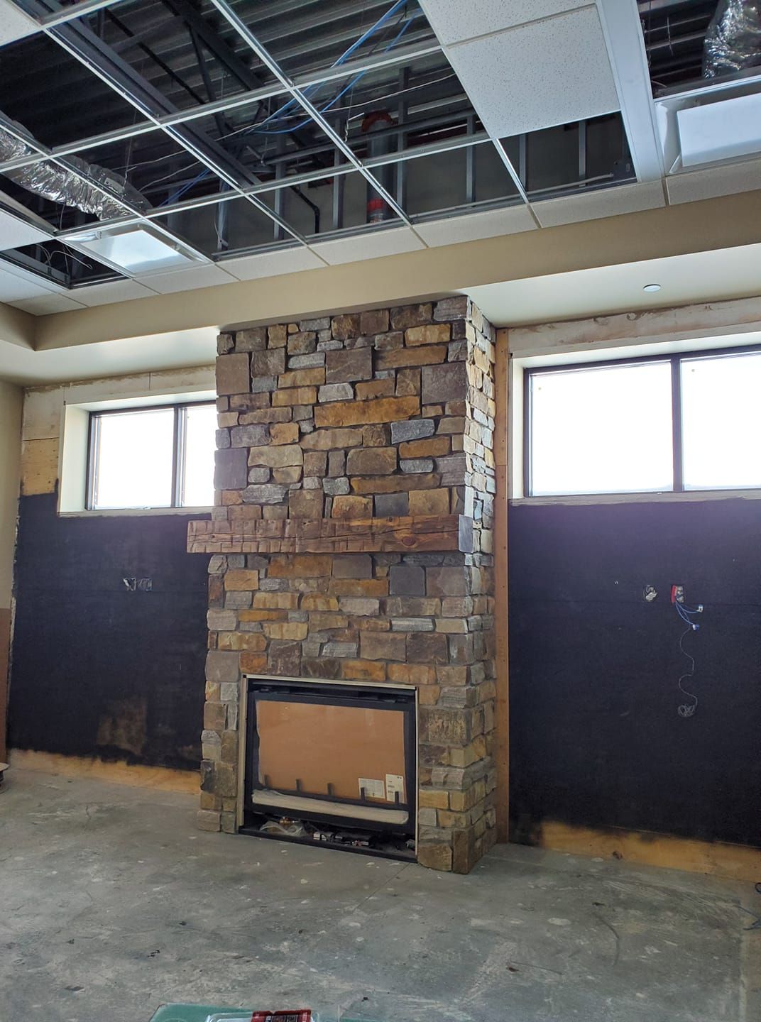 A stone fireplace in a room with a lot of windows