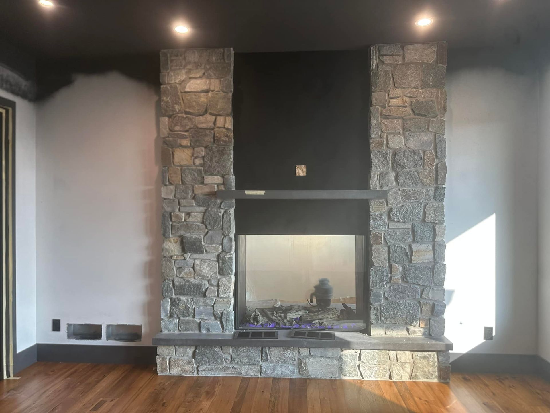 A large stone fireplace in a living room with hardwood floors